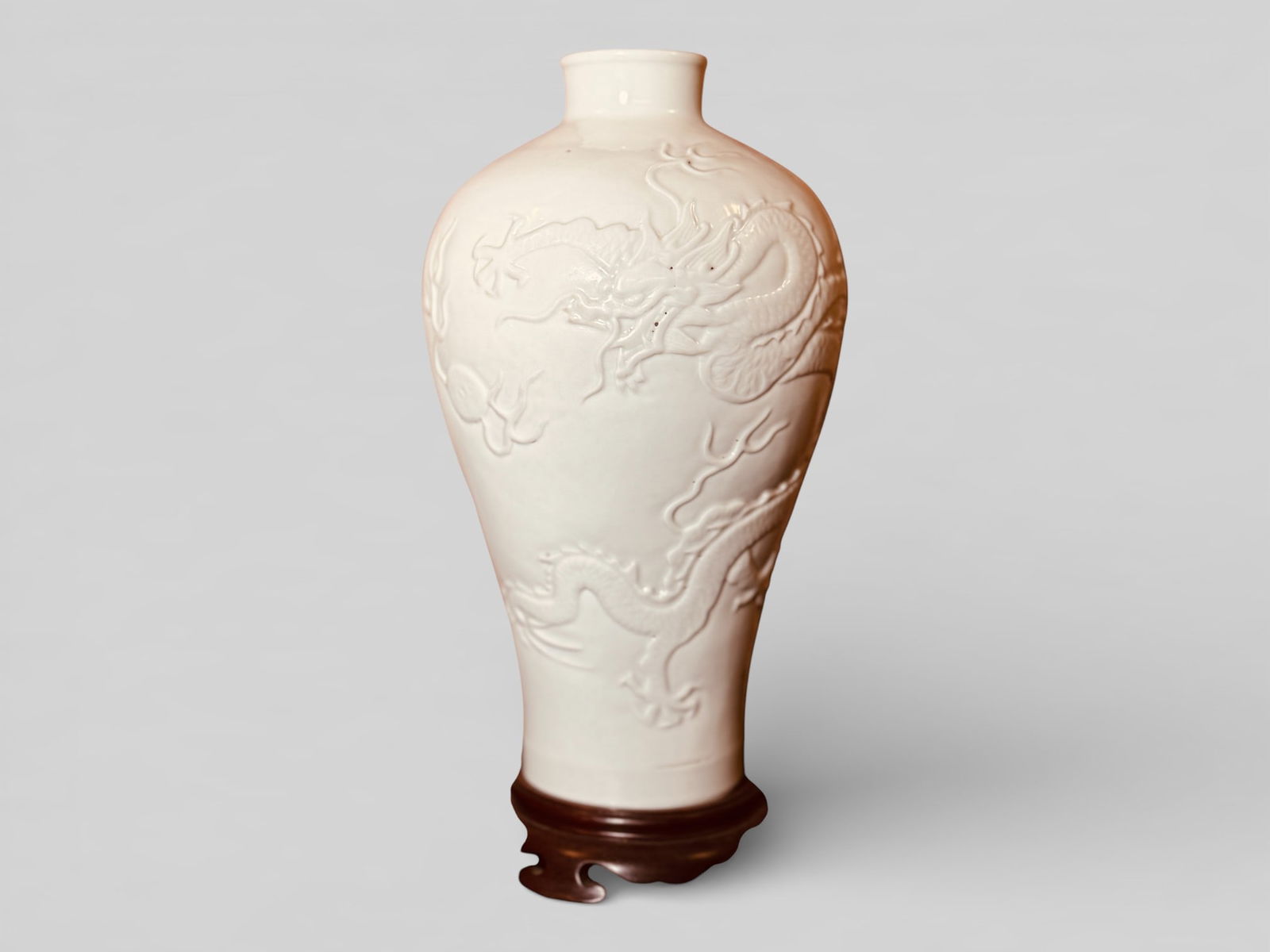 A Rare White-Glazed Relief-Decorated Vase,18th Century: A white glazed porcelain vase with moriage dragon motif, on hardwood base with old label, vase 10.75"ht Shipping: We offer in-house shipping services for most small items. This means that we will take