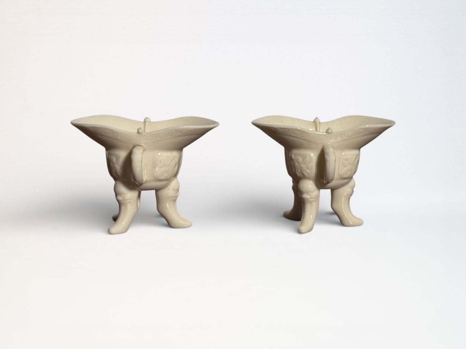 Pair of Chinese Dehua Blanc De Chine Porcelain Jue Wine Cups: Pair chinese dechua porcelain ju cups, tip of one cup pole on top has a small nick, otherwise in good condition, each cup 4.25"w 3.2"ht Shipping: We offer in-house shipping services for most small ite