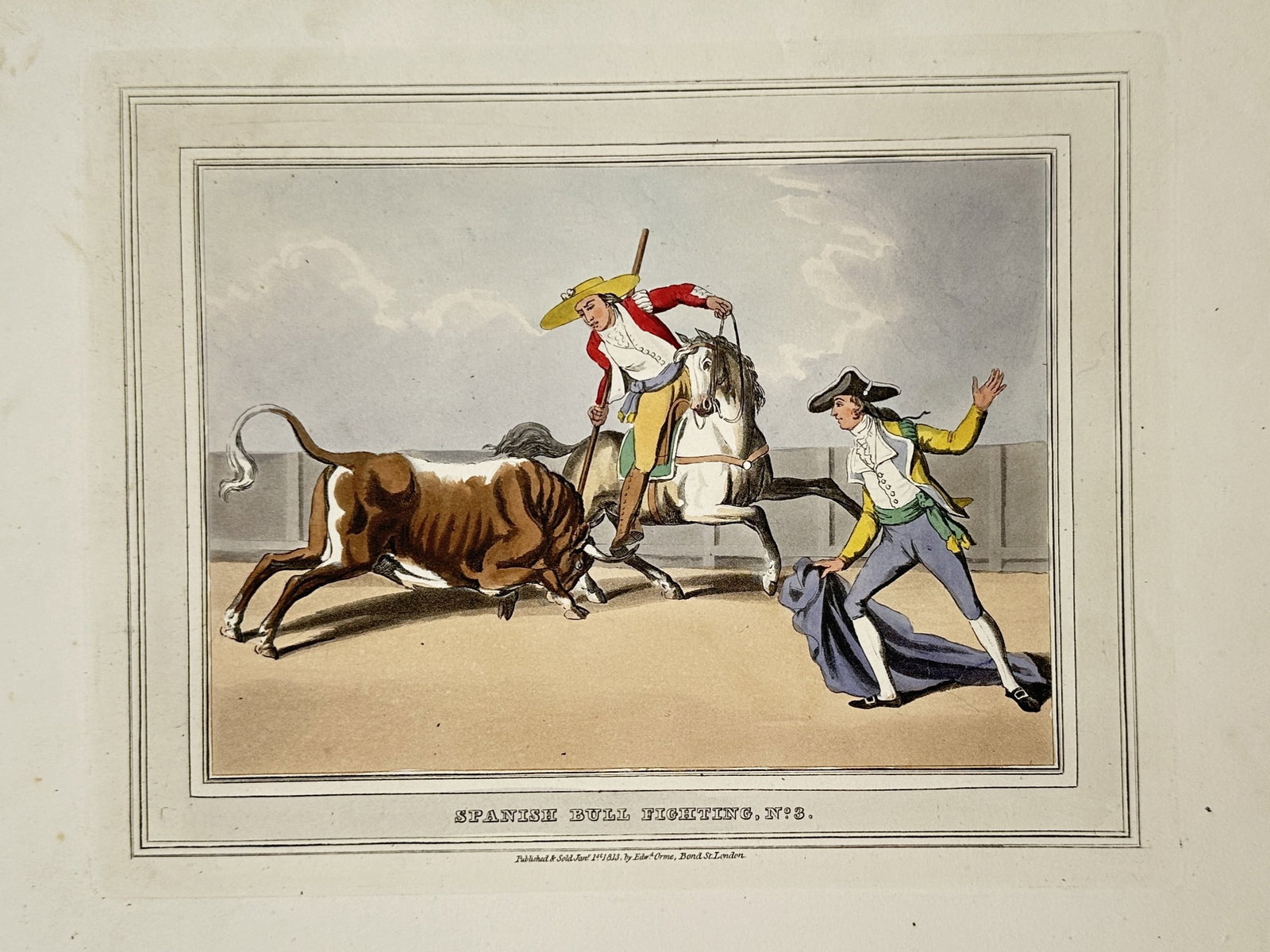 John Heaviside Clark (1771-1863) – View of Spanish Bull Fighting – Hand-coloured aquatint (1813): "Spanish Bull Fighting" depicts a dramatic scene in an arena where a bull charges toward a picador on horseback while a torero standing nearby manages a blue cape. This hand-coloured aquatint was publ