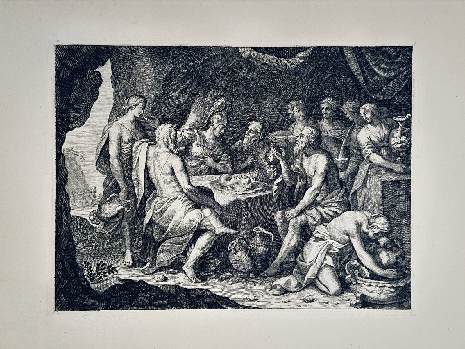 Charles Le Brun – Classical Banquet Scene within a Cave – Engraving (1680): Mythological Banquet This engraving presents a detailed classical composition depicting a group of draped figures and soldiers in helmets gathered around a table for a feast inside a rocky cavern or g