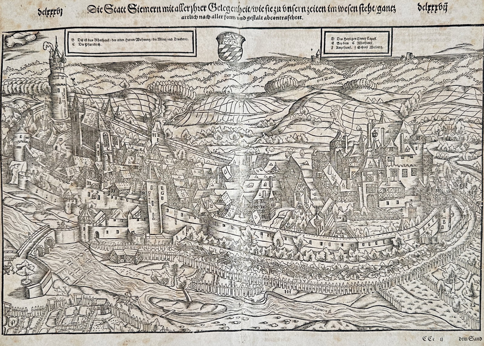 Sebastian Münster – Panoramic View of the City of Simmern – Woodcut (16th Century): "The City of Simmern with All Its Surroundings" presents a detailed sixteenth-century panoramic view depicting the fortified town of Simmern with its city walls, castle, residential buildings, and sur