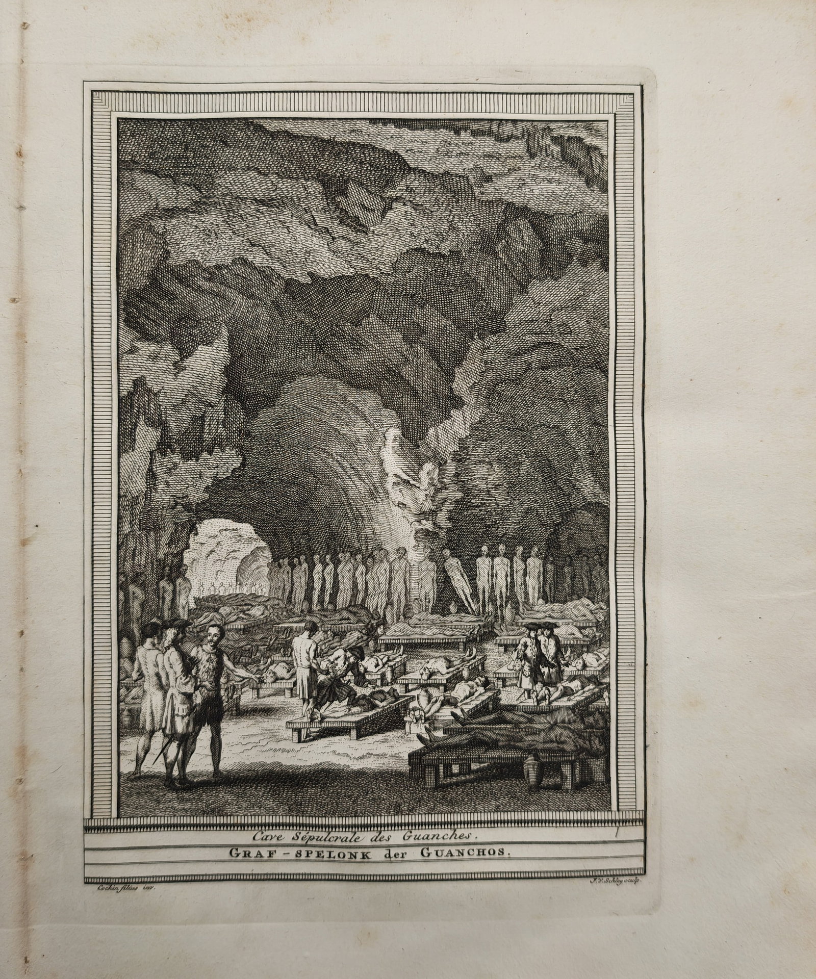 Jacob van der Schley – Guanche Sepulchral Cave in the Canary Islands – Engraving (18th Century): "Sepulchral Cave of the Guanches" presents an eighteenth-century ethnographic and historical view depicting European explorers examining mummified bodies resting on raised wooden platforms inside a de
