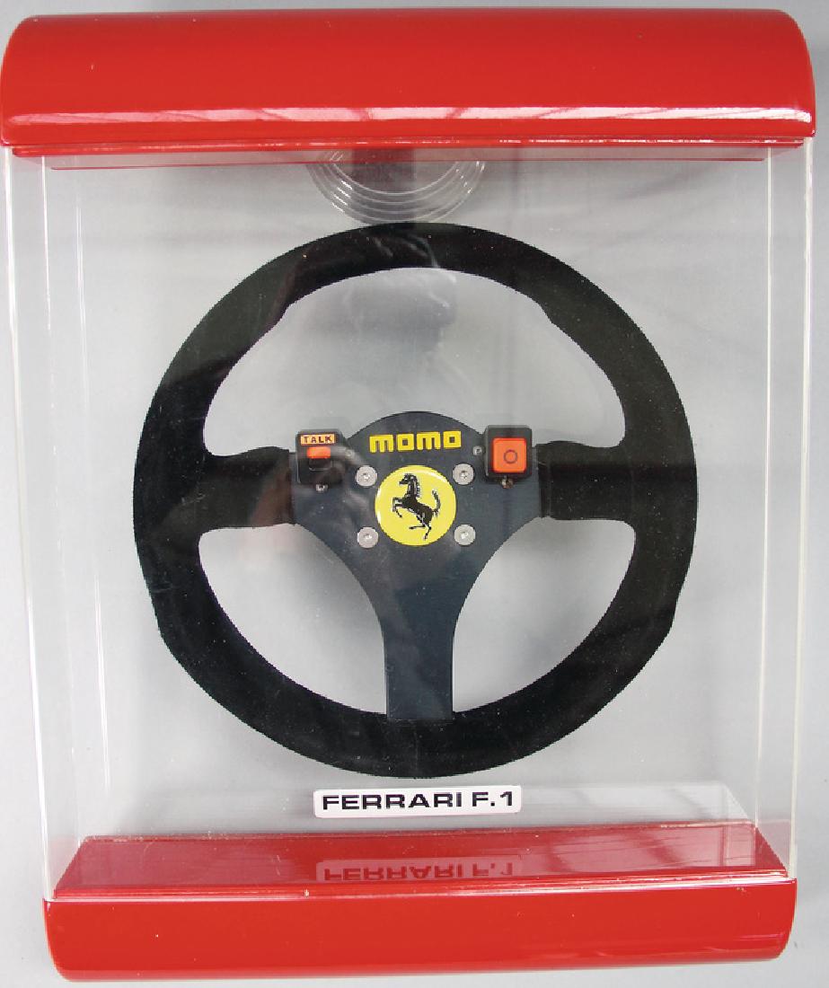 FERRARI/MOMO Original F1 steering wheel, year c. 1980: FERRARI/MOMO Original F1 steering wheel, year c. 1980 for drivers Alesi/Prost, in original glass cabinet/showcase, glass cabinet is slightly damaged at the right lower side, otherwise good condition,