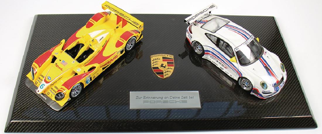 PORSCHE diorama consists of 2 1:18 model cars on a: PORSCHE diorama consists of 2 1:18 model cars on a carbon fiber board, model cars Porsche RS Spyder and Porsche 997 GT3 RS, format of the board c. 63 x 33 cm, in the middle with an embedded Porsche em