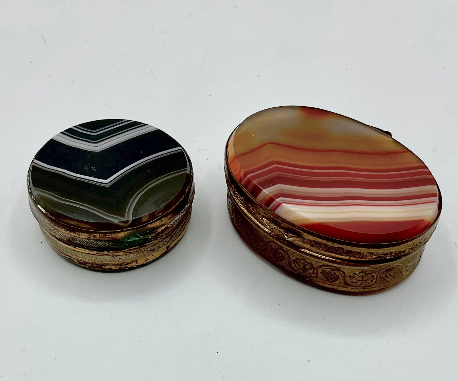 Set of two hard stone pill boxes,Agate and Carnelian: Nice set of oval and round boxes. Carnelian is slightly loose on a metal,requires fixation. Agate is opens and closes fine. Needs cleaning. All items come in original antique condition. Sold as is.