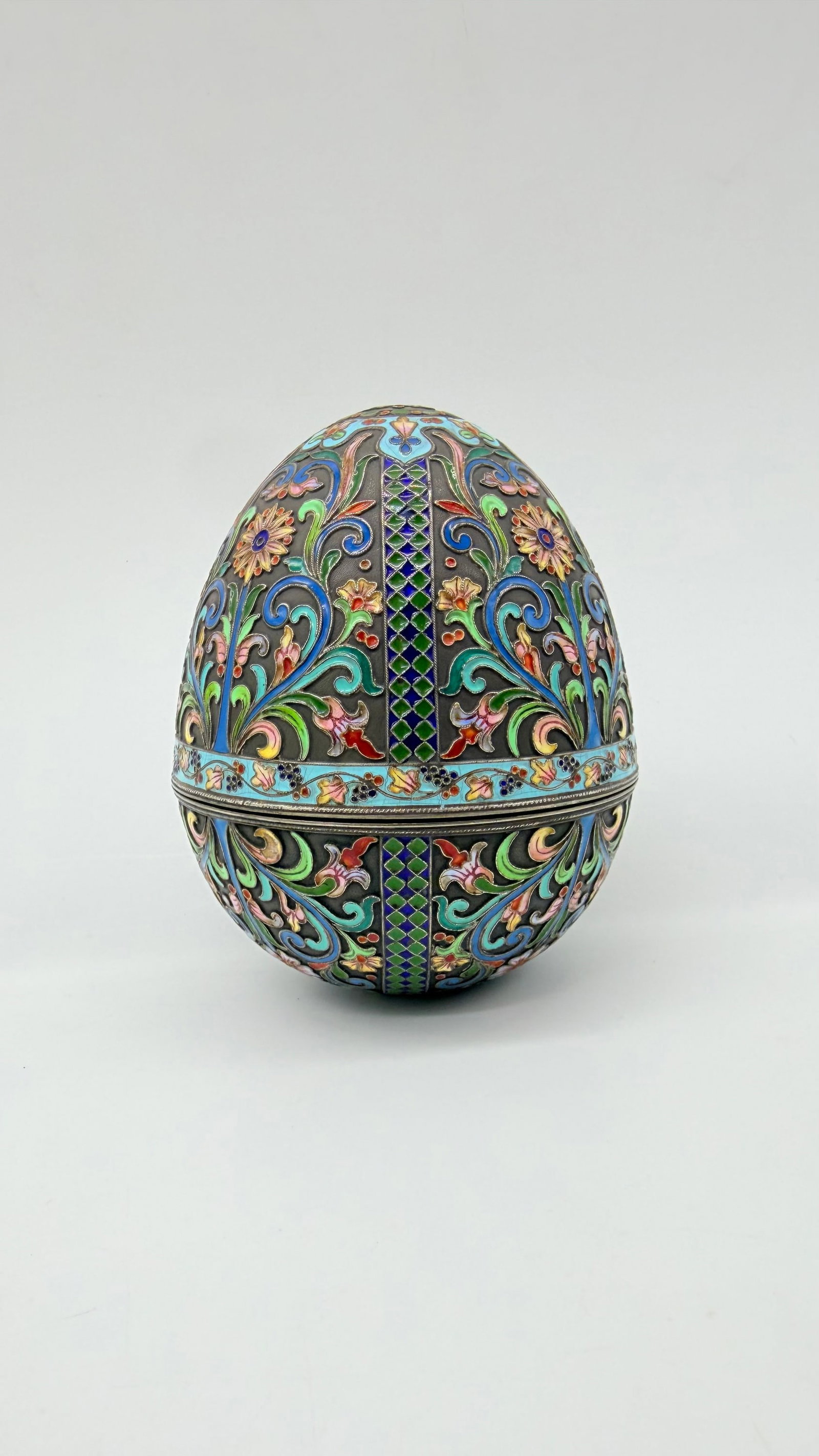 Large Silver-Plated and Cloisonné-Enamel Egg: Large egg-shaped box in silver-plated metal and cloisonné enamels.Polychrome decoration of leafy scrolls, stylized flowers, and geometric motifs in cloisonné enamels on a dark ground. Encircled at t