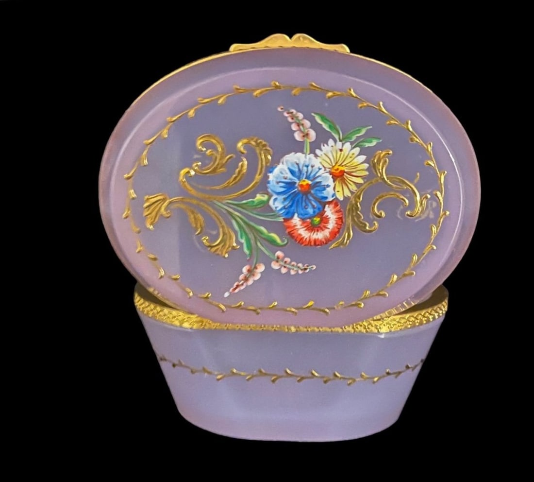 MURANO CENEDESE LILAC OPALINE GLASS HINGED BOX, 20TH CENTURY: An oval covered box in translucent pastel lilac/lavender opaline glass, the hinged lid set in a chased gilt-metal mount. Hand-painted in polychrome enamels and gold with a central bouquet of field flo