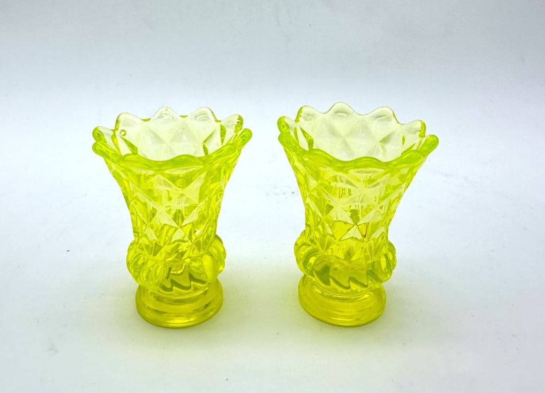 PAIR OF SMALL URANIUM GLASS VASES, LATE 19TH CENTURY: A pair of small vases crafted in yellow-green pressed uranium glass. Each piece features a flared body decorated with molded diamond pattern cuts, a lobed central ring, and a wavy scalloped rim, resti