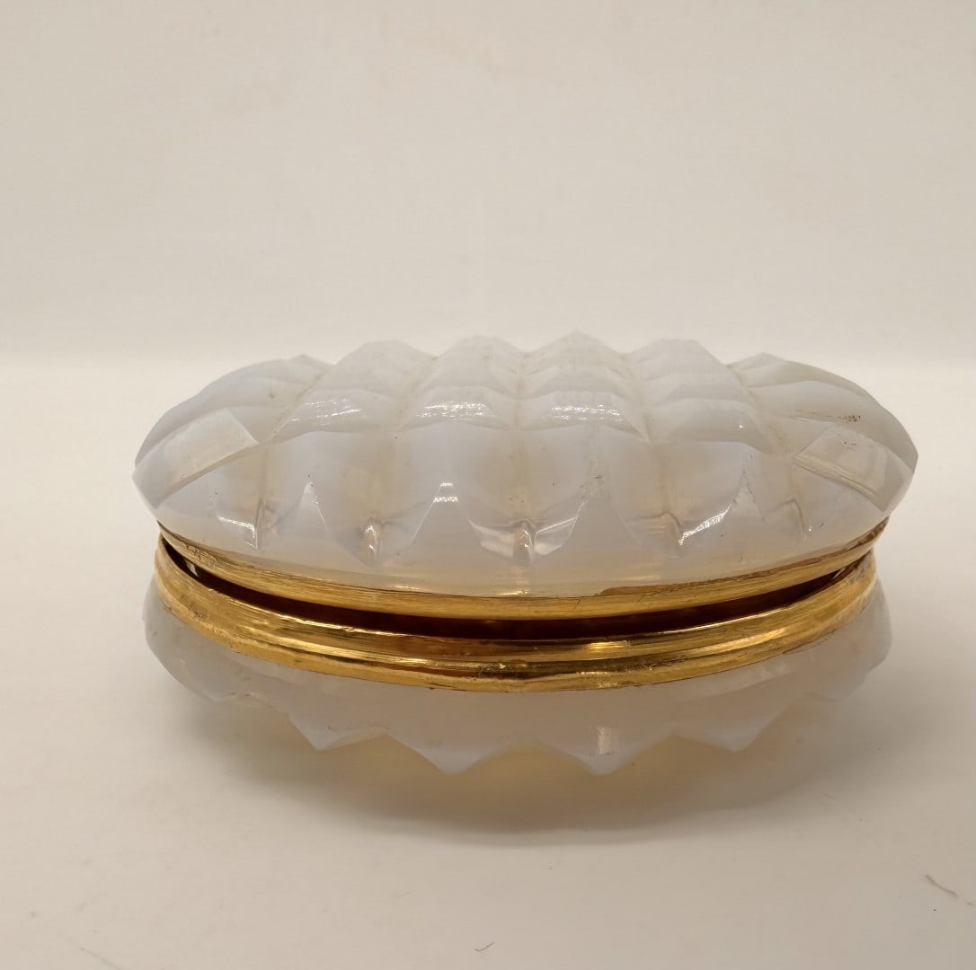 MILK WHITE OPALINE GLASS BOX WITH GILT-BRONZE MOUNT, CHARLES X PERIOD, CIRCA 1820–1830: A small circular trinket box crafted in milk-white opaline glass featuring a translucent soap-bubble appearance. The cover and base are cut in a raised chessboard diamond-point pattern. The two halves