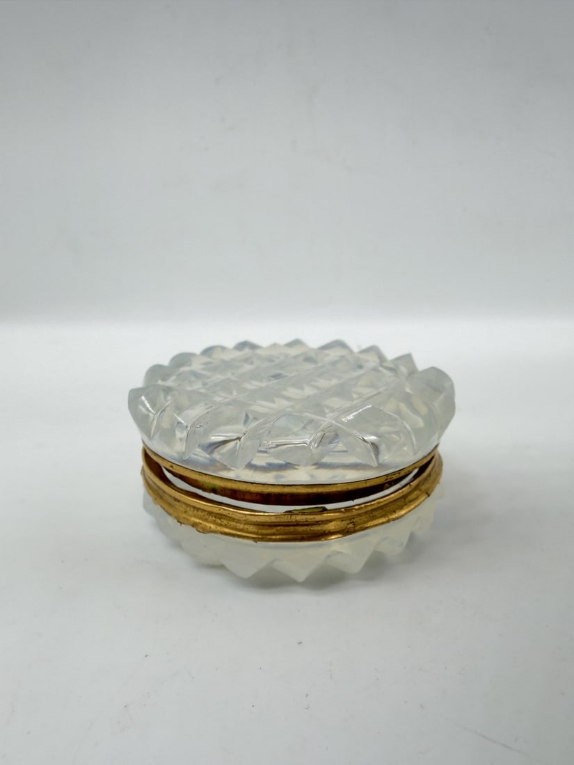 FRENCH OPALINE GLASS BOX WITH GILT-BRONZE MOUNT, CHARLES X PERIOD, CIRCA 1820–1830: A small circular trinket or pill box crafted in translucent white opaline glass with a soap-bubble appearance. The lid and base feature cut diamond-point geometric patterns across the outer surface. T