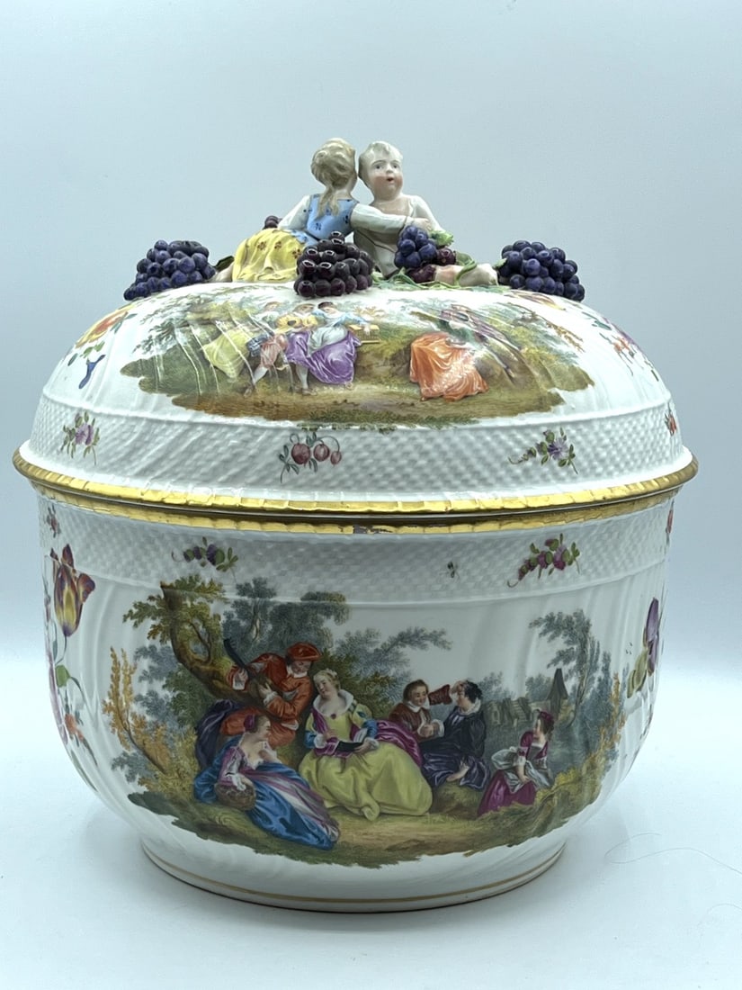 DRESDEN PORCELAIN COVERED CENTERPIECE BOWL, 19TH CENTURY: Covered centerpiece bowl featuring hand-painted romantic pastoral scenes of figures in 18th-century attire within landscape settings, interspersed with floral sprays (Deutsche Blumen). The body and li