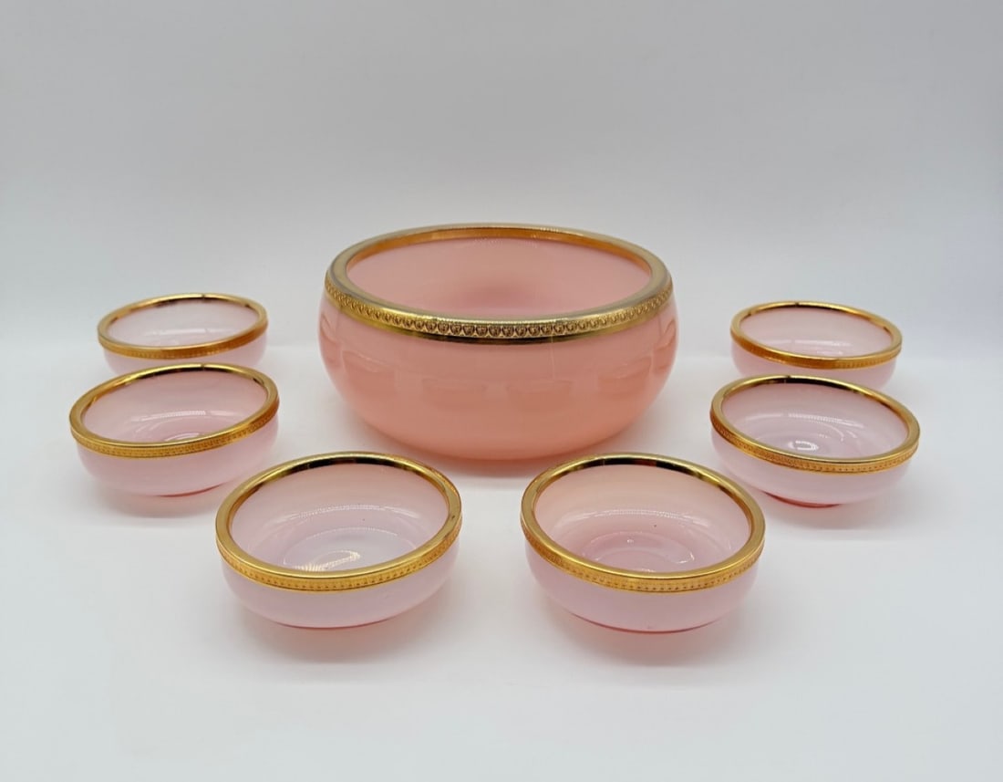 MURANO OPALINE GLASS FRUIT BOWL SET WITH GILT-BRONZE MOUNTS, 20TH CENTURY: A seven-piece fruit set comprising one large central serving bowl and six matching individual bowls crafted in light pink opaline glass. Each bowl features a smooth, rounded body fitted with a broad g