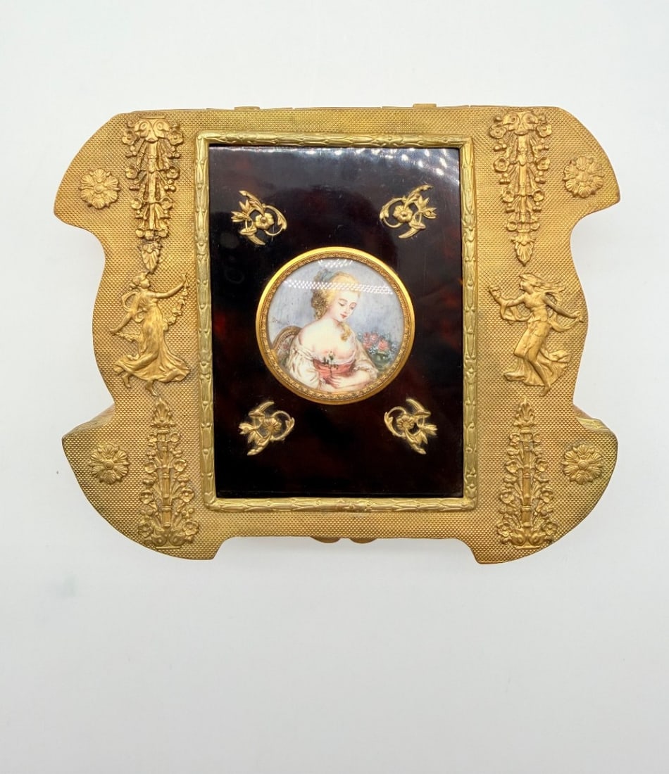 FRENCH GILT-BRONZE JEWELRY CASKET WITH MINIATURE PORTRAIT PLAQUE, 19TH CENTURY: A French gilt-bronze (ormolu) jewelry casket of shaped rectangular outline with indented corners. The hinged lid features a central rectangular faux-tortoiseshell inset mounted with a circular hand-pa