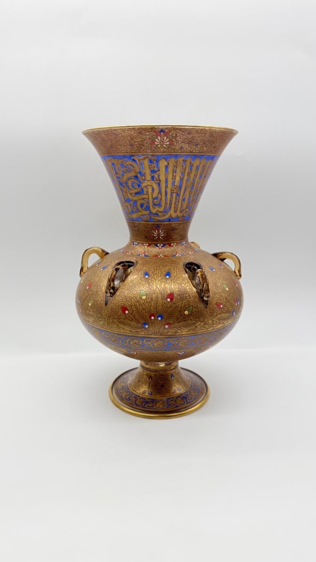 MAMLUK REVIVAL ENAMELED AND GILDED GLASS MOSQUE LAMP, 19TH CENTURY: A large glass mosque lamp (mishkat) featuring rich gilded scrolling foliage, polychrome enamel accents, and a flared neck inscribed with a calligraphic Quranic verse in gilded Arabic script against a 