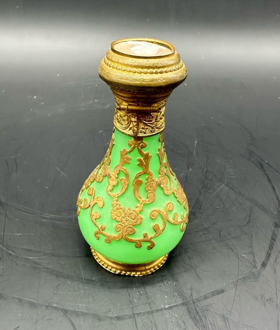 FRENCH GREEN OPALINE GLASS PERFUME BOTTLE WITH ORMOLU MOUNTS AND CAMEO LID, NAPOLEON III PERIOD,: Scent bottle crafted in vibrant apple-green opaline uranium glass (ouraline). The baluster-form body is overlaid with intricate gilt-bronze (ormolu) filigree cage work depicting Rococo scrolling folia