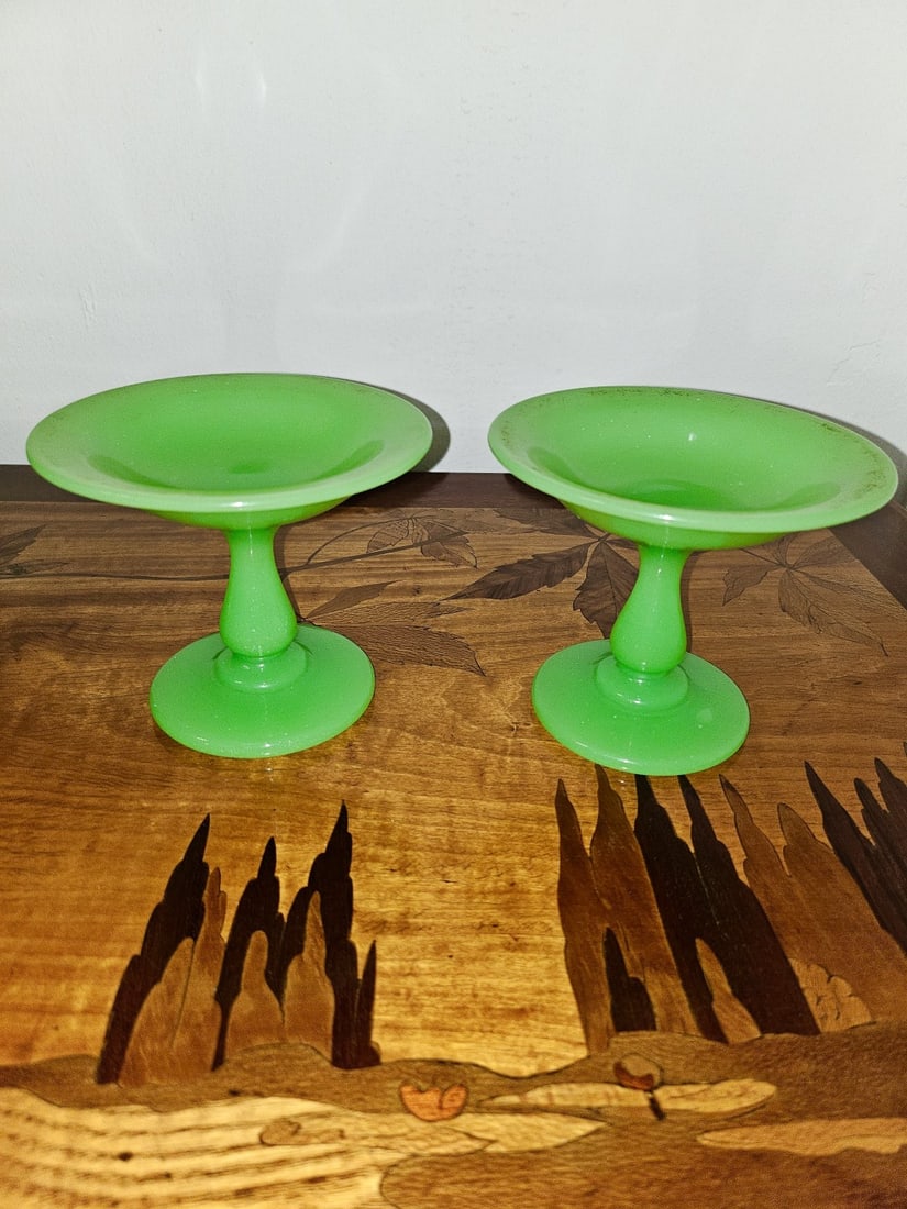 PAIR OF FRENCH GREEN OPALINE GLASS TAZZAS, NAPOLEON III PERIOD, CIRCA 1850–1870: Pair of small French opaline glass pedestal dishes (tazzas or coupes sur piédestal) in vibrant apple-green opaline. Each piece features a broad, shallow saucer top with a softly upturned rim, raised 