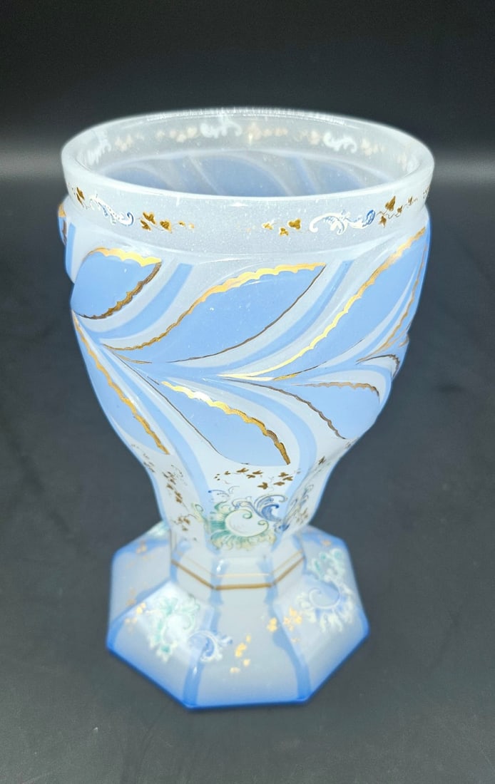 BOHEMIAN ENAMELED AND MOULDED ALABASTER OPALINE GLASS BEAKER, HARRACH, CIRCA 1840: A footed beaker in light blue and white overlay alabaster opaline glass. The body features a molded relief pattern of stylized leaf motifs encircling the upper section, outlined with gilded borders. T