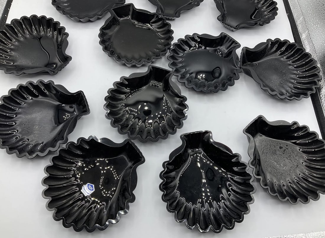 SET OF TWELVE BLACK GLASS SHELL-SHAPED DISHES, MANUFACTURED BY CRISTALLERIA VETRI (COSTA VETRI),: A set of twelve dishes in opaque black glass, press-molded in the shape of a scallop shell with fluted radial ribs and a contoured rim. One dish retains the original factory paper label marked "Crista