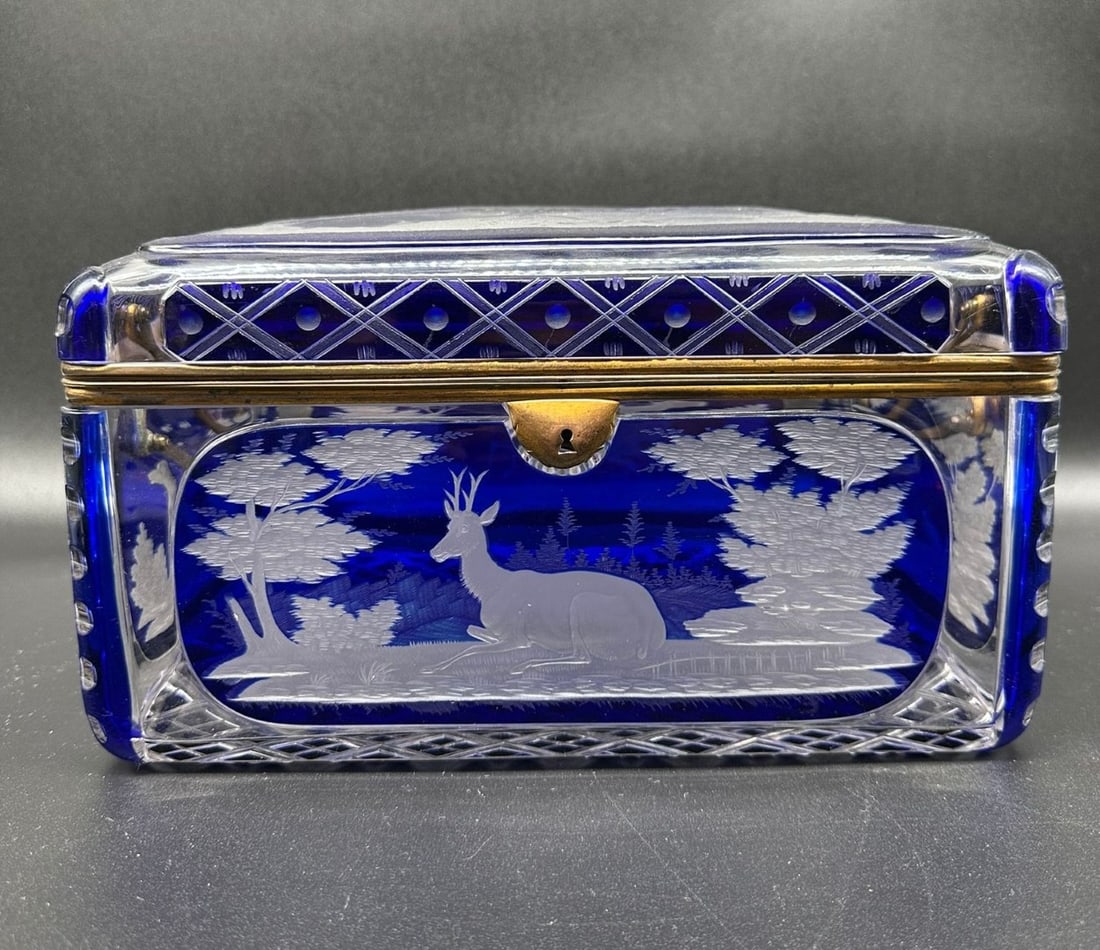 BOHEMIAN COBALT BLUE OVERLAY ENGRAVED GLASS CASKET, MID-19TH CENTURY: A large rectangular glass casket in cobalt blue overlay crystal (Überfangglas). The hinged lid and four side panels feature deeply wheel-engraved woodland scenes depicting stags, deer, and birds set 