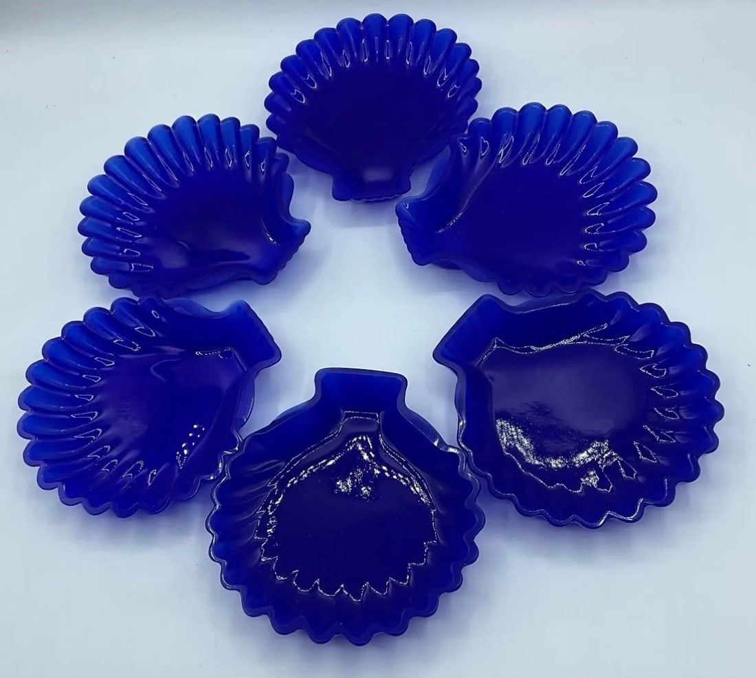 SET OF TWELVE ITALIAN SAPPHIRE BLUE GLASS SHELL-SHAPED DISHES, MURANO, LATE 20TH CENTURY: A set of twelve dishes in translucent sapphire blue opalescent glass, press-molded in the shape of a scallop shell with fluted radial ribs and a scalloped rim. The pieces bear the original factory lab
