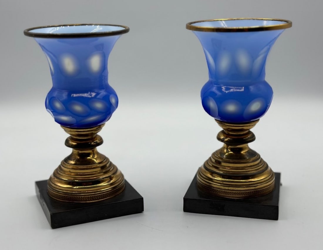 PAIR OF FRENCH BLUE OPALINE GLASS VASES ON GILT-BRONZE BASES, NAPOLEON III PERIOD, CIRCA 1850–1870: A pair of small vases (vases cornet) in blue opaline glass with cut-to-white coin-spot (thumbprint) optics. Each flared trumpet-shaped vessel features a bulbous lower section and a gilded brass rim, m