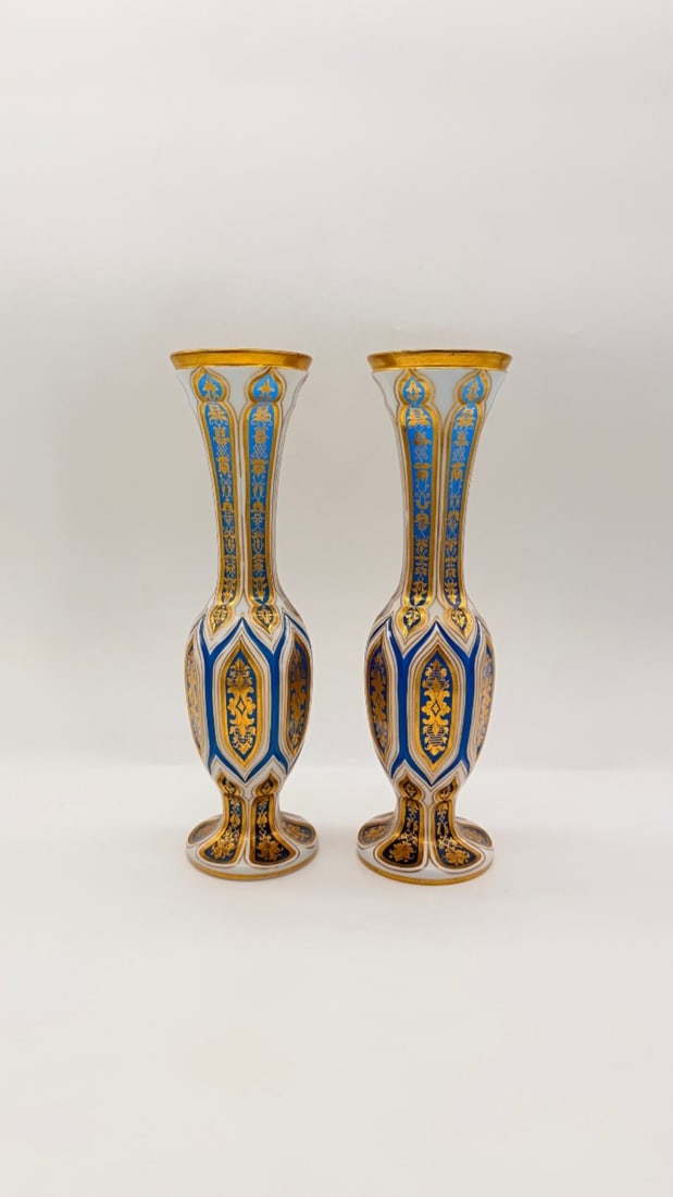 PAIR OF BOHEMIAN TURQUOISE AND OPALINE OVERLAY GLASS VASES, 19TH CENTURY: A pair of baluster-form vases in cased overlay crystal with flared, trumpet-shaped necks and circular pedestal bases. The body features cut-to-clear geometric panels, pointed arches, and lancet window
