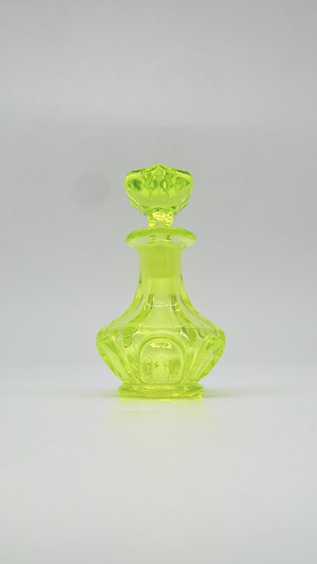 BOHEMIAN BIEDERMEIER URANIUM GLASS PERFUME BOTTLE, ATTRIBUTED TO HARRACH OR RIEDEL, CIRCA: A small perfume bottle in bright yellow-green uranium glass (AnnaGelb / Annagelb-grün). The bulbous body features wide, facet-cut panels and arch-shaped printies, rising to a narrow neck with a flare