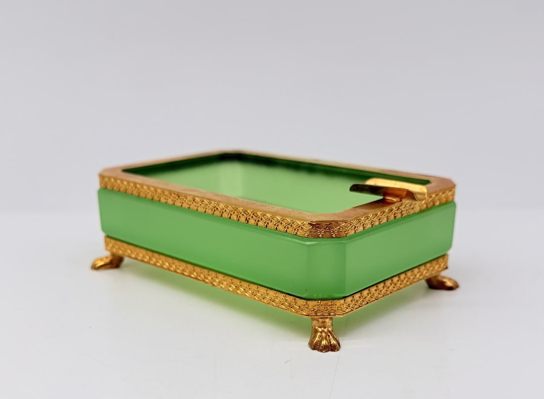 FRENCH GREEN OPALINE GLASS ASHTRAY WITH GILT-BRONZE MOUNTS, 19TH CENTURY: A rectangular ashtray or trinket dish crafted in bright apple-green opaline glass with clipped corners. The glass body is encased in a fine gilt-bronze (ormolu) frame featuring chased lattice borders,