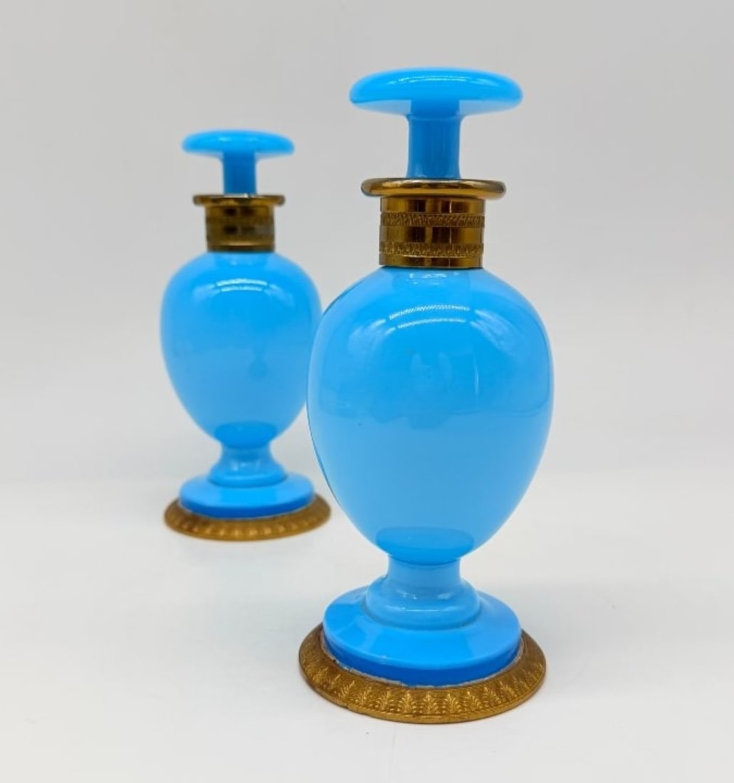 Pair Of Azure Blue Opaline Perfume Flasks With Gilt Bronze Mounts, Charles X Period: A pair of perfume bottles on azure-blue opaline pedestals, the necks and bases embellished with chiselled gilded bronze mountings, the stoppers in matching opaline with disc-shaped handles.France. Cha