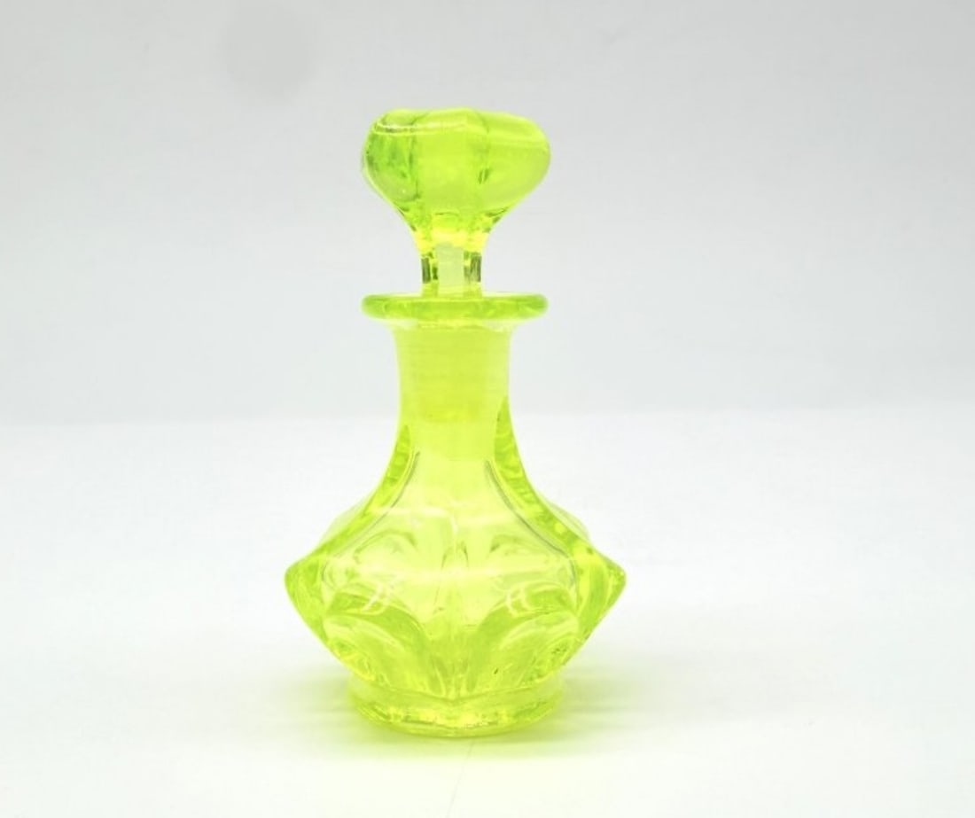 Bohemian Yellow-green Uranium Glass Scent Bottle, Biedermeier Period, Circa 1840: A baluster-shaped perfume bottle with bevelled sides and a fluted base, made of translucent yellow-green Ouraline glass, complete with its original faceted stopper decorated with twisted ribs.Bohemia.