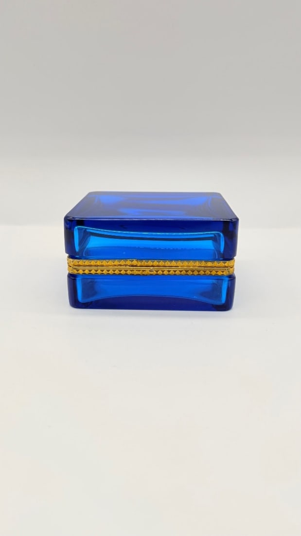 LARGE FRENCH SAPPHIRE BLUE GLASS CASKET BOX WITH GILT-BRONZE MOUNTS, ART DECO PERIOD: Rectangular hinged casket box in polished sapphire blue crystal with thick, faceted side walls and clean geometric lines. The box is fitted with a finely chased gilt-bronze (ormolu) hinged rim mount f