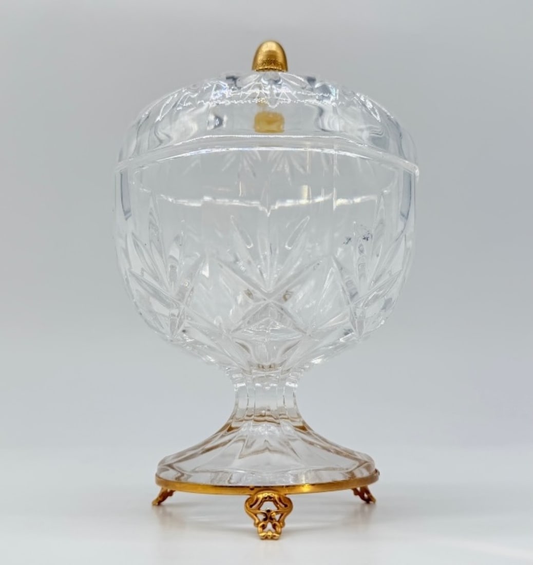 FRENCH CUT-CRYSTAL SWEETMEAT JAR WITH GILT-BRONZE MOUNT, ART NOUVEAU PERIOD: A covered crystal sweetmeat jar or bonbonnière featuring a deeply cut geometric pattern of stars and diamond points (pointes de diamant). The vessel rests on a short faceted stem and a circular foot 