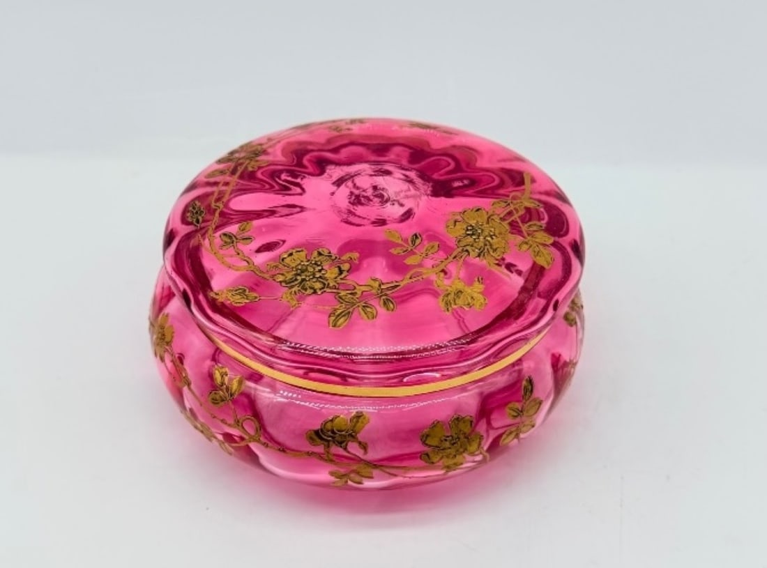FRENCH CRANBERRY CRYSTAL COVERED BOX WITH GOLD ENAMEL FLORAL DECORATION, BACCARAT, 19TH CENTURY: A circular covered box crafted in vibrant cranberry red (cristal rubis) crystal with subtle fluted lobing. The lid and body are finely hand-painted in gold enamel with trailing wild rose vines, flower