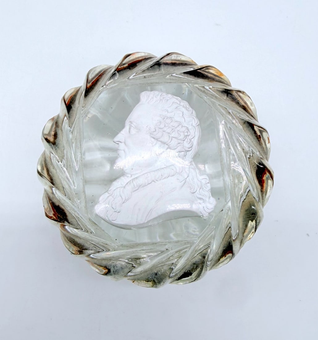 FRENCH BACCARAT CUT-CRYSTAL SNUFF BOX WITH SULPHIDE PROFILE OF BEAUMARCHAIS, LOUIS-PHILIPPE PERIOD: circular crystal snuff box featuring spiraled, swirled cut-facet borders and gilt-copper hardware. The lid encapsulates a white ceramic cameo (sulphide / incrustation) portraying the profile portrait 