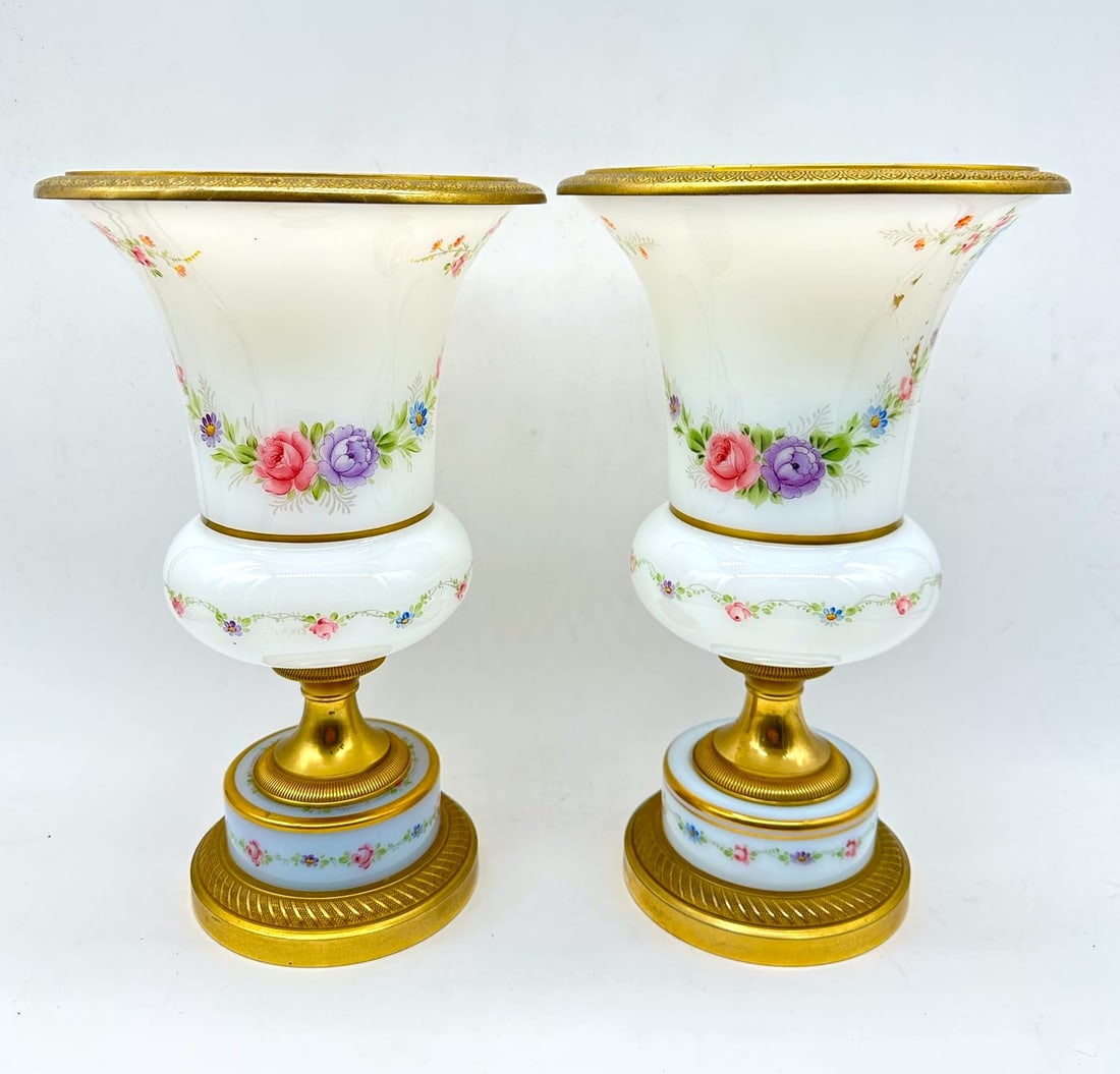 PAIR OF FRENCH OPALINE MEDICI GLASS VASES WITH GILT-BRONZE MOUNTS, NAPOLEON III PERIOD: A pair of white opaline glass urn-form vases inspired by the classic Medici shape, each featuring a flared rim mounted with an engraved gilt-bronze ring and supported on a multi-stepped gilt-bronze ba
