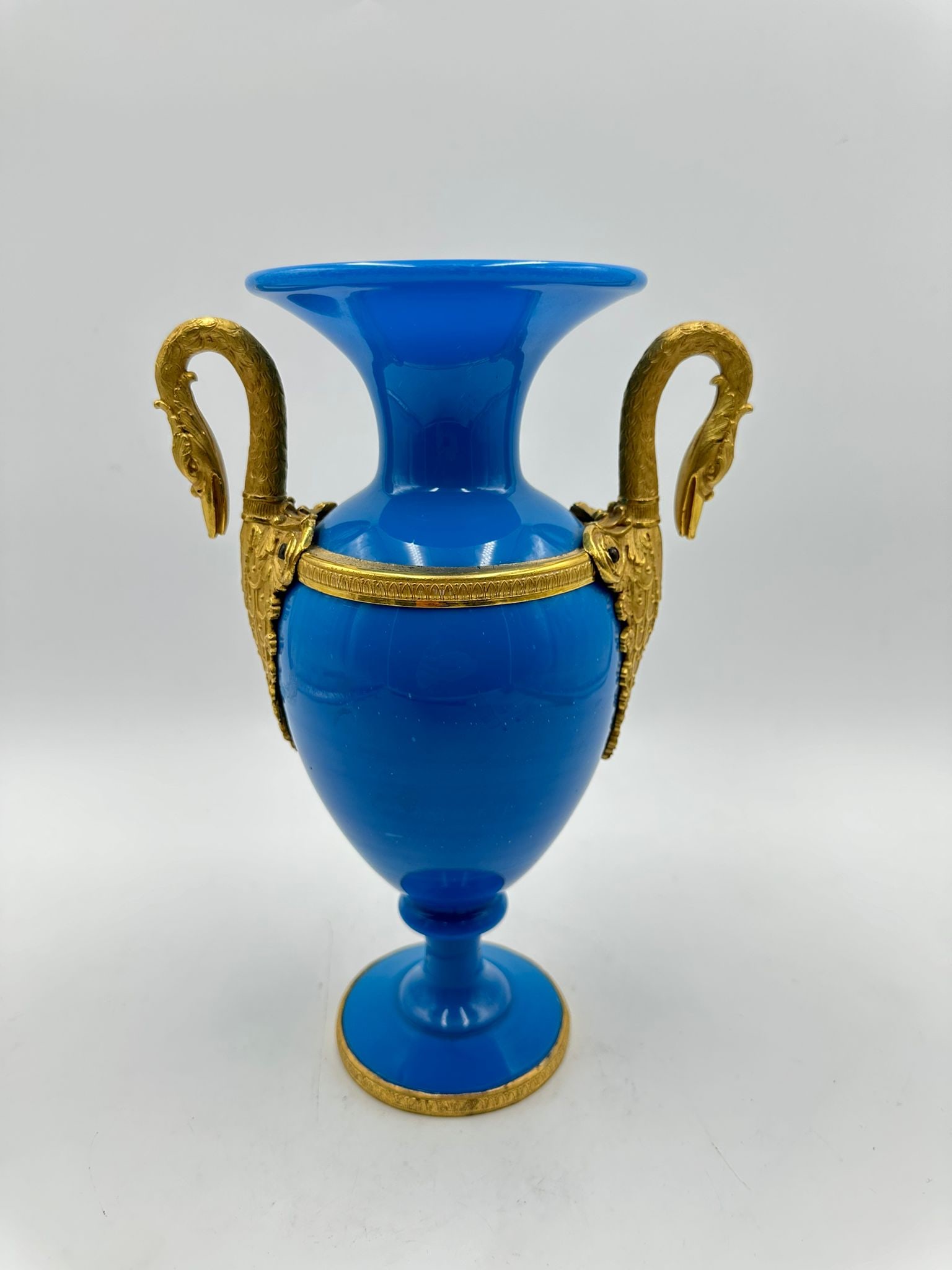 FRENCH TURQUOISE OPALINE AND ORMOLU TWO-HANDLED VASE, CHARLES X PERIOD: A turquoise-blue opaline glass baluster-shaped vase featuring finely chased gilt-bronze (ormolu) handles sculpted as graceful swan necks, encircled by a chased rim collar and resting on a circular opa
