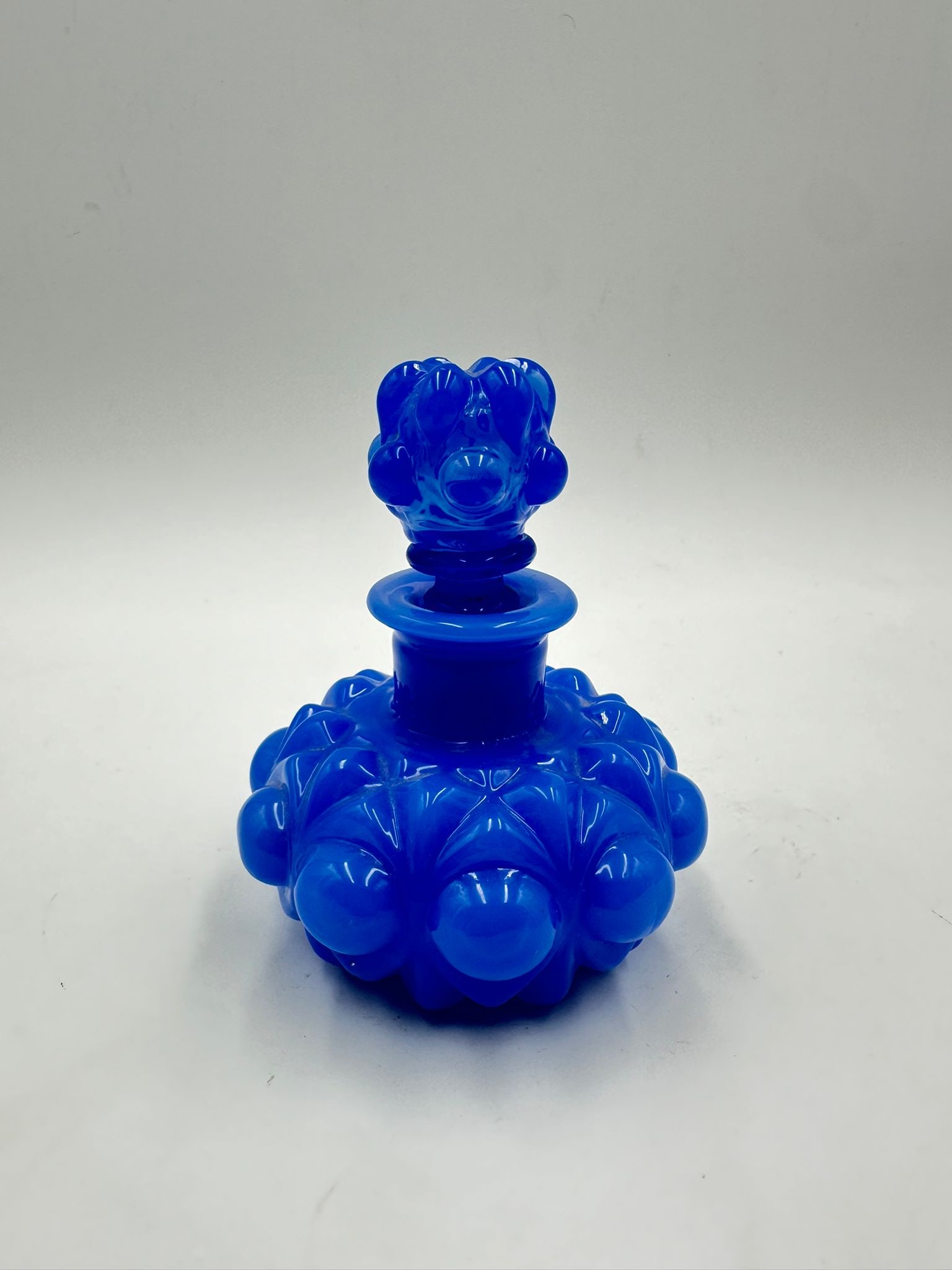 FRENCH BLUE OPALINE GLASS PERFUME BOTTLE, CHARLES X PERIOD: A vibrant blue opaline glass perfume bottle of squat, rounded form, molded with prominent cabochon and diamond-point reliefs, complete with its original matching crown-shaped stopper.France. Charles X