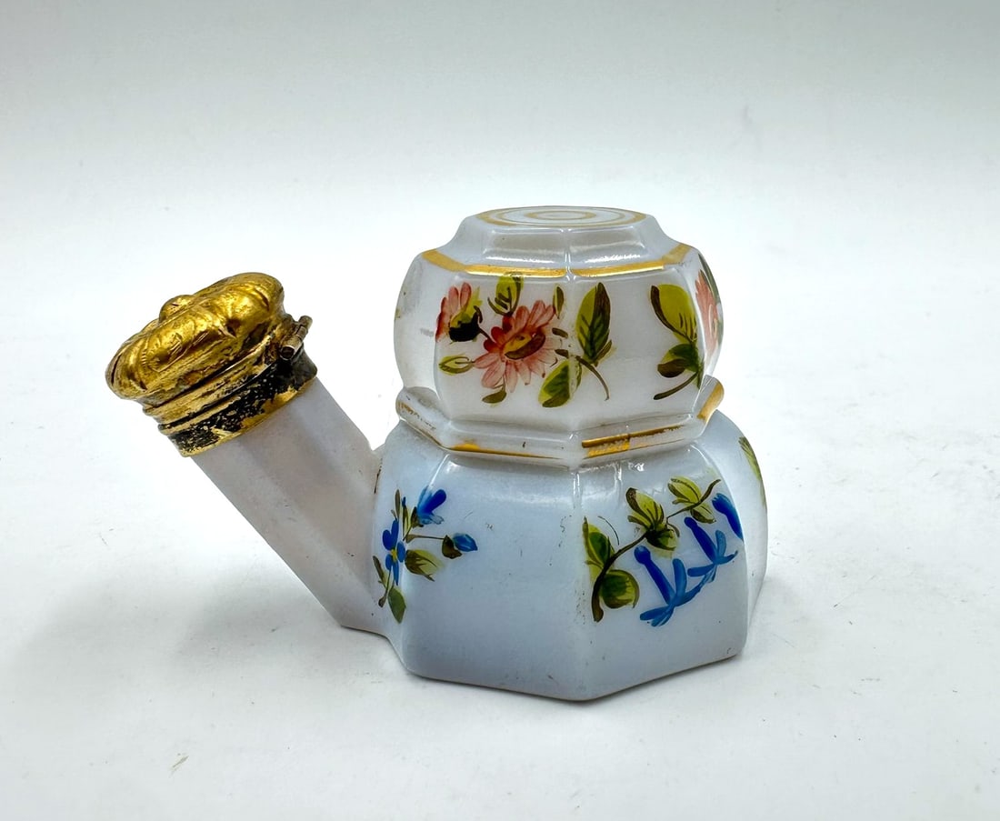 FRENCH WHITE OPALINE TRAVELLING PERFUME BOTTLE, CHARLES X PERIOD: A French white opaline glass travelling perfume bottle of octagonal form with hand-painted floral decoration and gilded highlights, featuring an angled spout fitted with a hinged gilt-bronze crown-sha