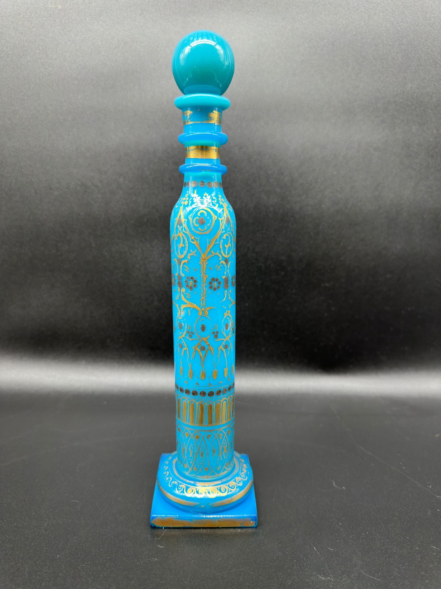 FRENCH CHARLES X TURQUOISE OPALINE GLASS PERFUME BOTTLE: Tall cylindrical opaline glass scent bottle in vivid turquoise blue, terminating in a matching spherical stopper and resting on a square pedestal base. The body and stopper are richly decorated with h