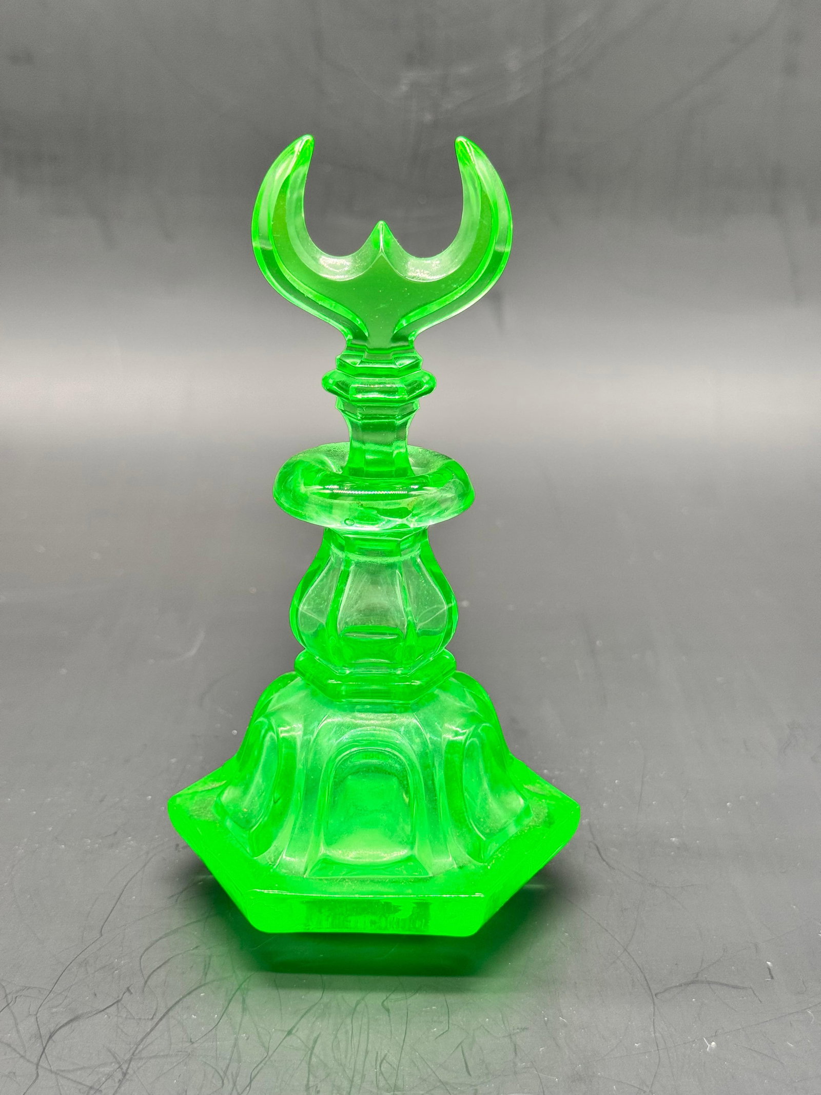 BOHEMIAN URANIUM GLASS PERFUME BOTTLE FOR THE MIDDLE EASTERN MARKET: Bohemian uranium glass scent bottle of vibrant apple-green color, crafted with a wide molded hexagonal base and faceted baluster neck. It is topped with a distinct stopper carved in the shape of a cre