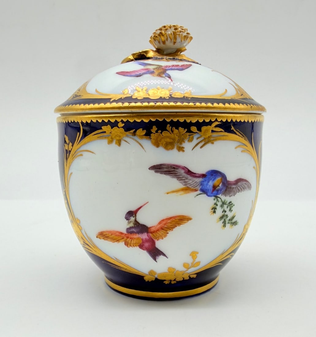 VINCENNES PORCELAIN COVERED SUGAR BOWL, "POT À SUCRE CALABRE": A soft-paste porcelain covered sugar bowl (pot à sucre Calabre) featuring polychrome enameling of birds in flight within gilt cartouches framed by palm fronds and flowering branches, set against a la