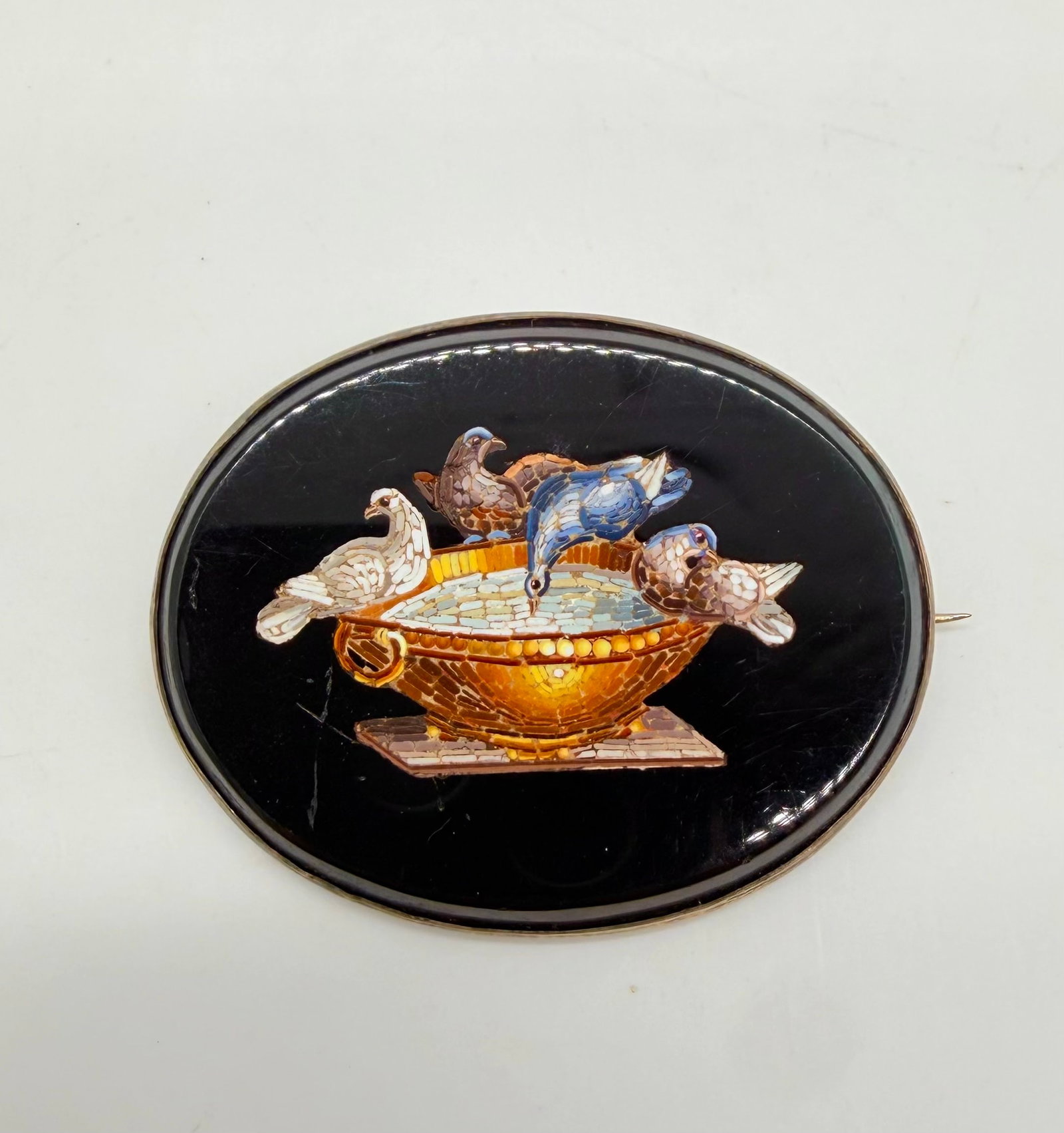 19TH-CENTURY ITALIAN MICROMOSAIC BROOCH "PLINY'S DOVES": Italy, circa 1860 (Grand Tour Souvenir)An oval black glass or onyx brooch set in a silver frame (silver tested), featuring a fine spun-glass micromosaic (tesserae) depicting "Pliny's Doves" (also know