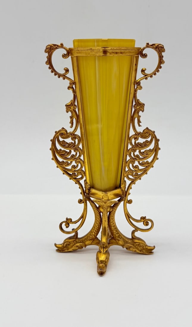 YELLOW OPALINE GLASS VASE WITH GILT BRONZE RETICULATED MOUNTS: A yellow opaline glass cornet-shaped vase encased within a gilt bronze (ormolu) frame. The framework features reticulated scrolling foliage, openwork side handles, and is raised on a tripod base suppo