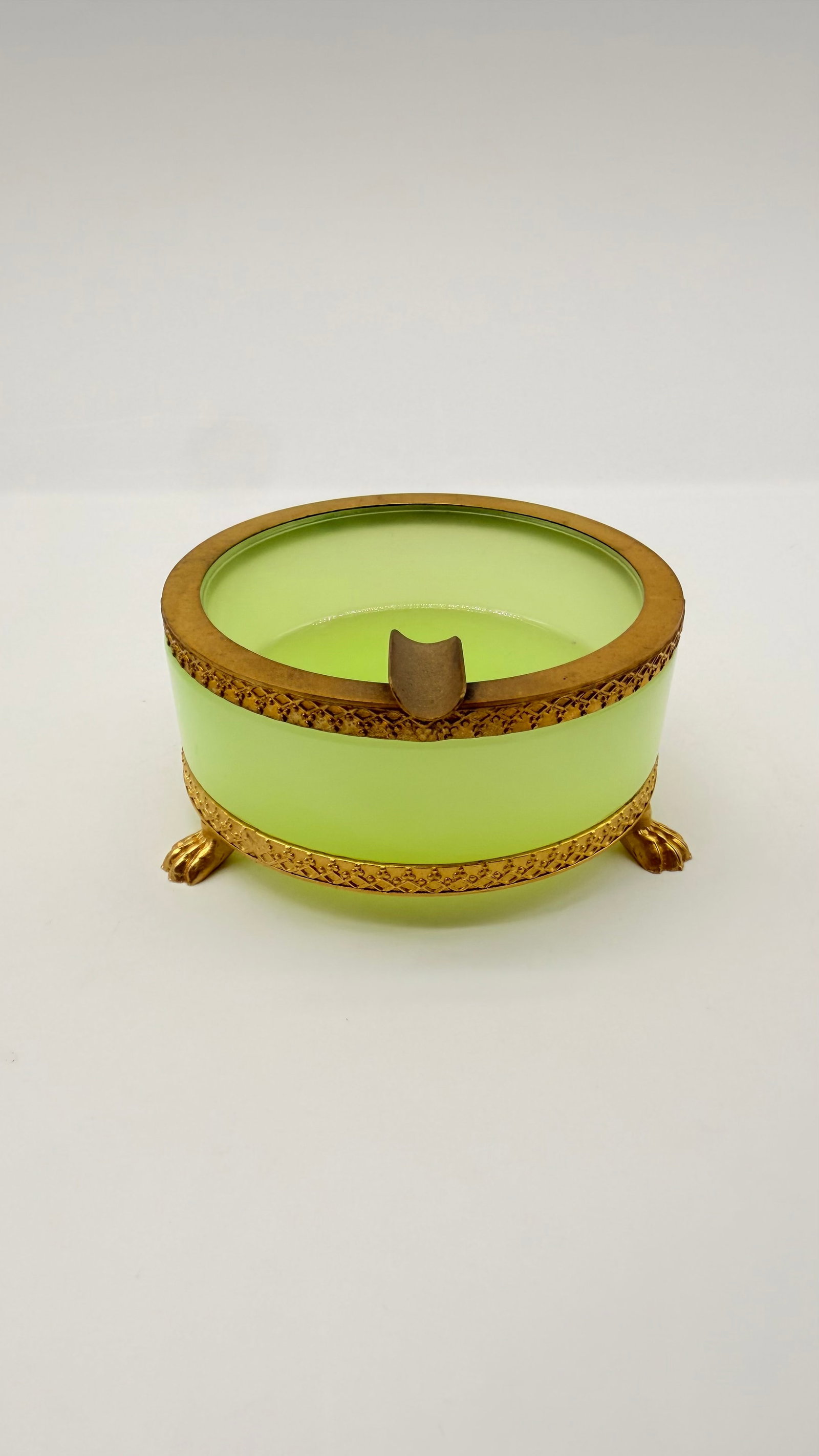 MURANO YELLOW OPALINE GLASS ASHTRAY: Italian Murano round ashtray crafted in chartreuse yellow opaline glass. Mounted with a chased gilt bronze rim featuring an integrated cigarette rest and a decorative patterned base rim supported on t