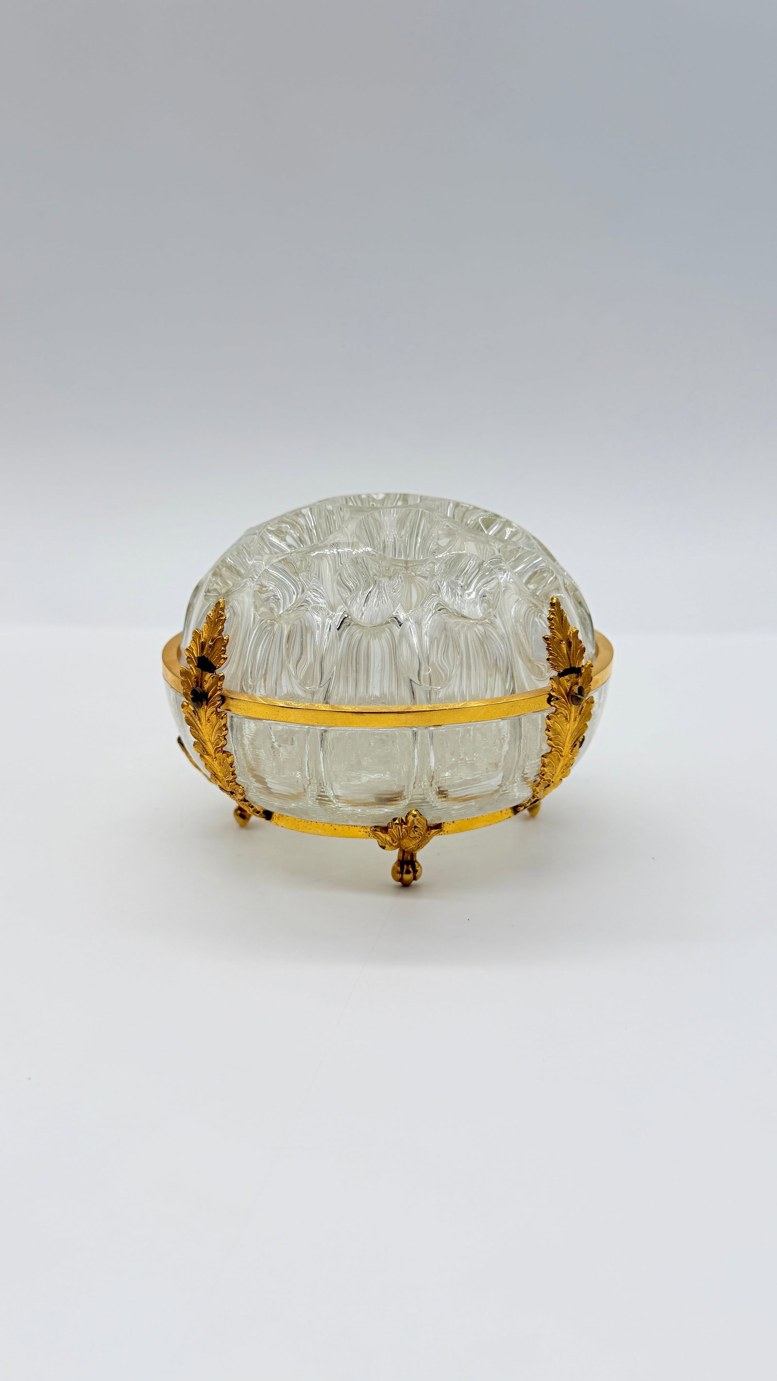19TH-CENTURY FRENCH BACCARAT PRESSED GLASS BOWL IN GILT BRONZE MOUNT: Rounded bowl in molded ribbed glass featuring a beaded and starburst pattern. Enclosed within a finely chased gilt bronze (ormolu) armature adorned with acanthus leaves, resting on four scroll feet an