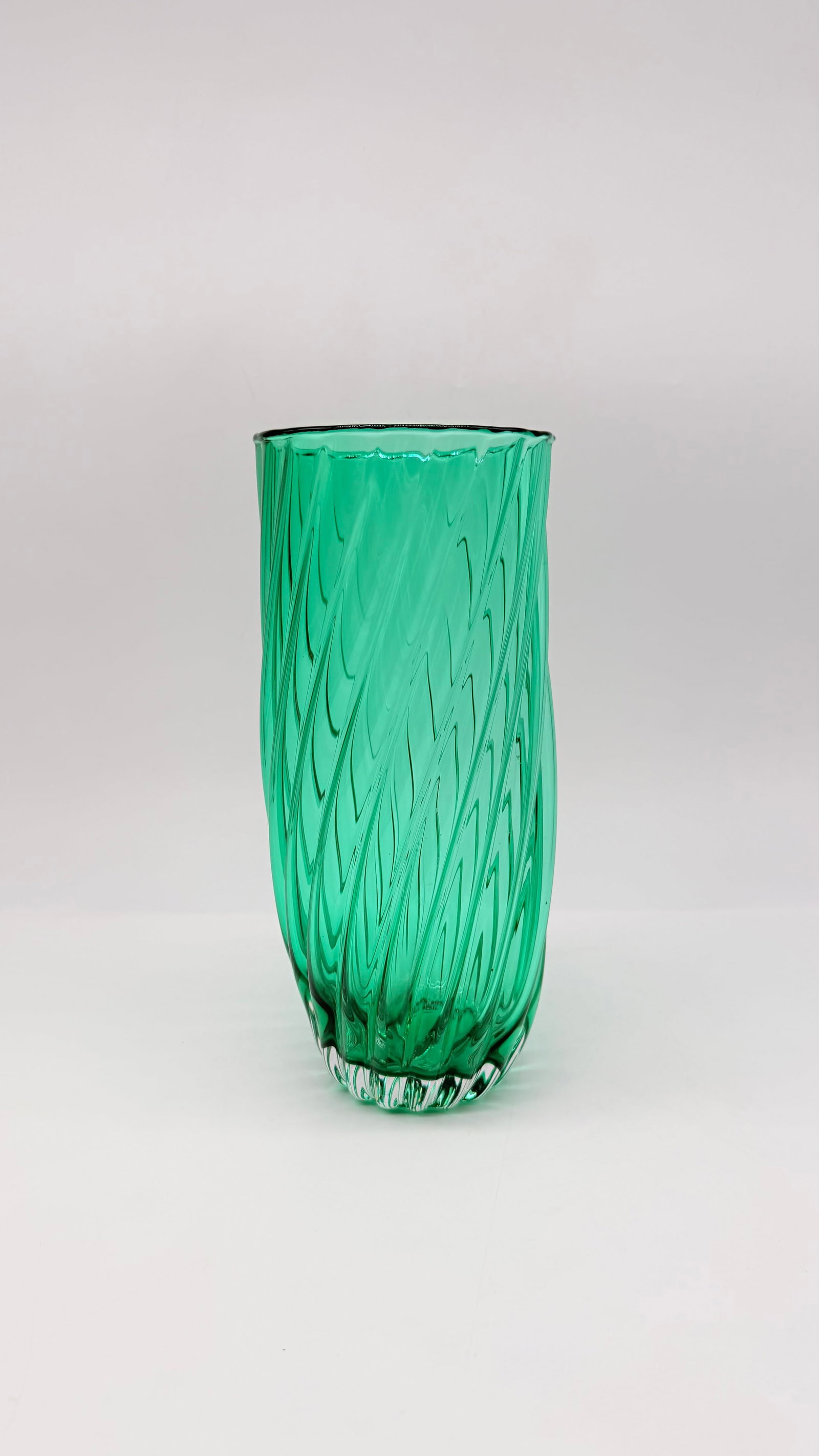 VINTAGE MURANO GREEN MOULDED GLASS SWIRL TUMBLER OR VASE: A vintage cylindrical tumbler or vase in vibrant emerald green glass, featuring an upside-down display showing a relief-molded dynamic spiral swirl pattern.Italie. Murano. 20th century.H_29 cm Very go