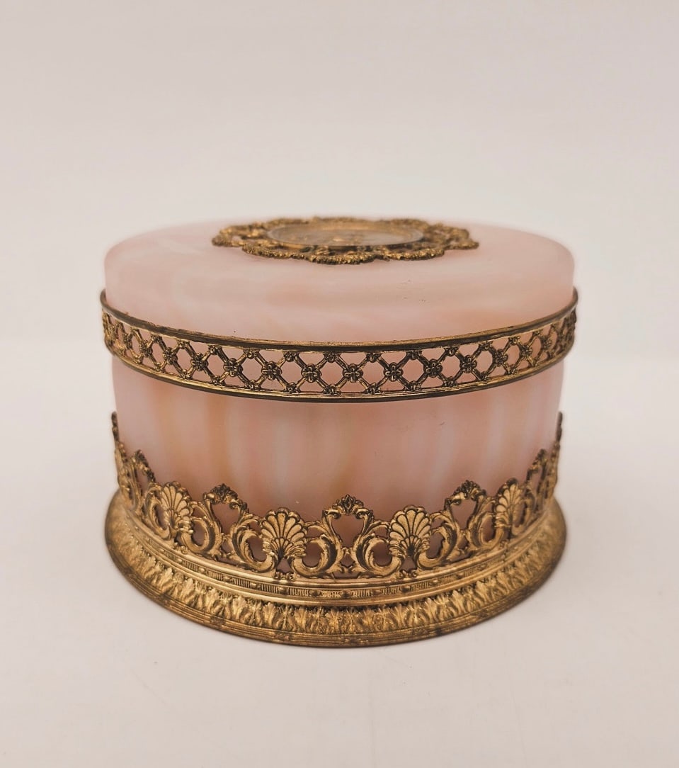 19TH-CENTURY PINK GLASS PASTE AND GILT BRONZE DRESSER BOX: A 19th-century circular powder/trinket box in marbled pink glass paste. Fitted with gilt bronze (ormolu) mounts including a pierced foliate gallery at the base, a lattice rim trim, and a lid set with 