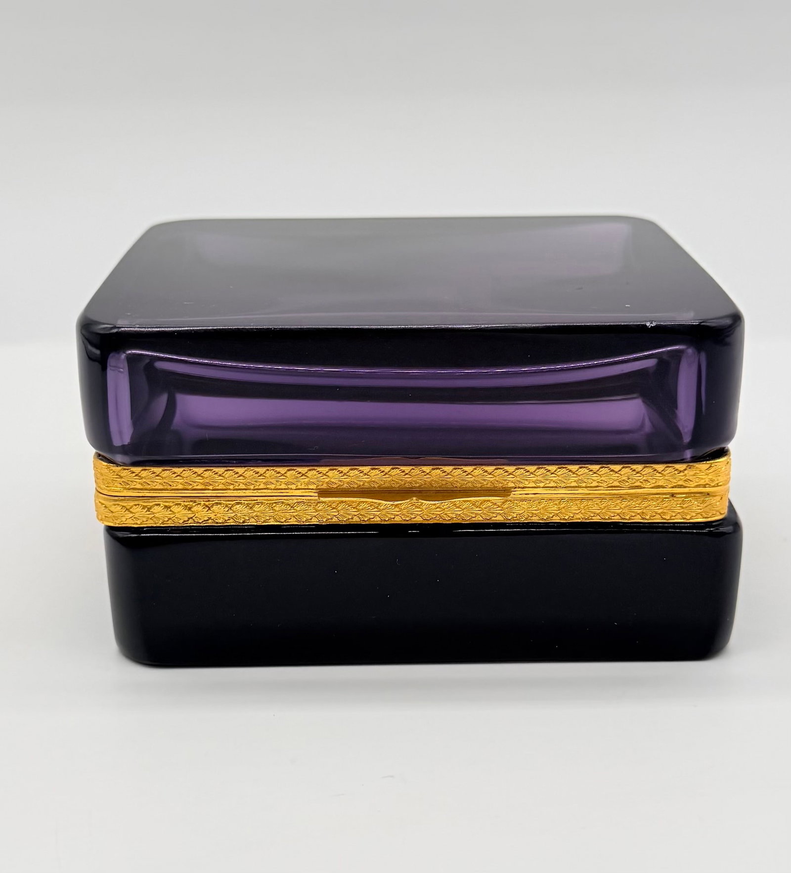 19TH-CENTURY AMETHYST CRYSTAL HINGED CASKET: A 19th-century rectangular hinged jewelry box made of rich deep amethyst/purple-colored glass or crystal, fitted with an intricately chased gilt-brass or gilt-bronze (ormolu) hinged rim collar.France.