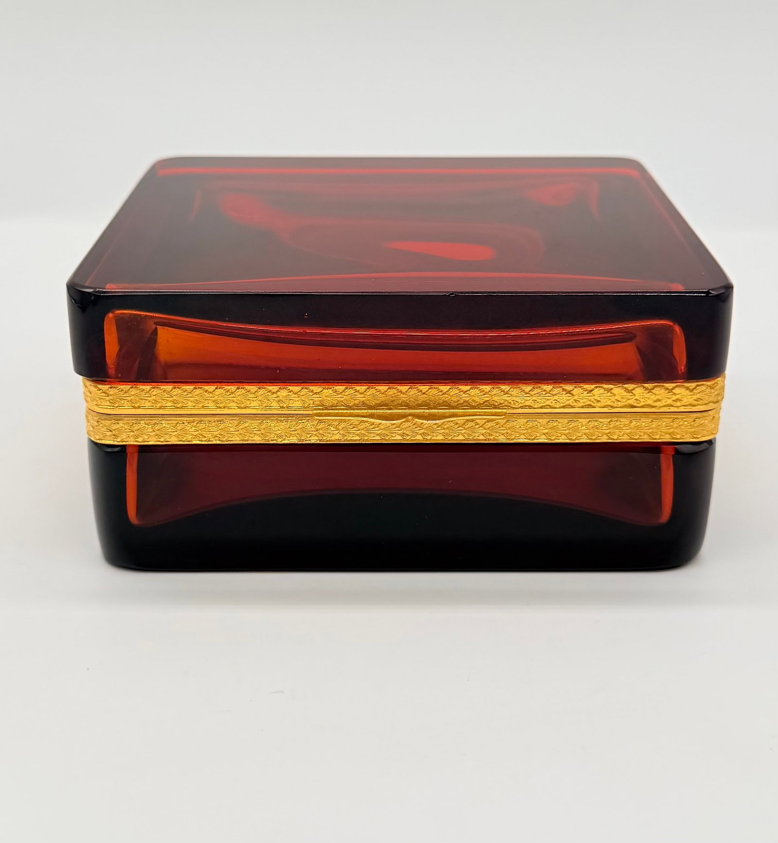 19TH-CENTURY AMBER/RED CRYSTAL HINGED CASKET: A 19th-century rectangular hinged jewelry box made of rich deep red or amber-toned glass or crystal, fitted with a chased gilt-brass or gilt-bronze (ormolu) hinged rim collar.France. 19th century (Nap