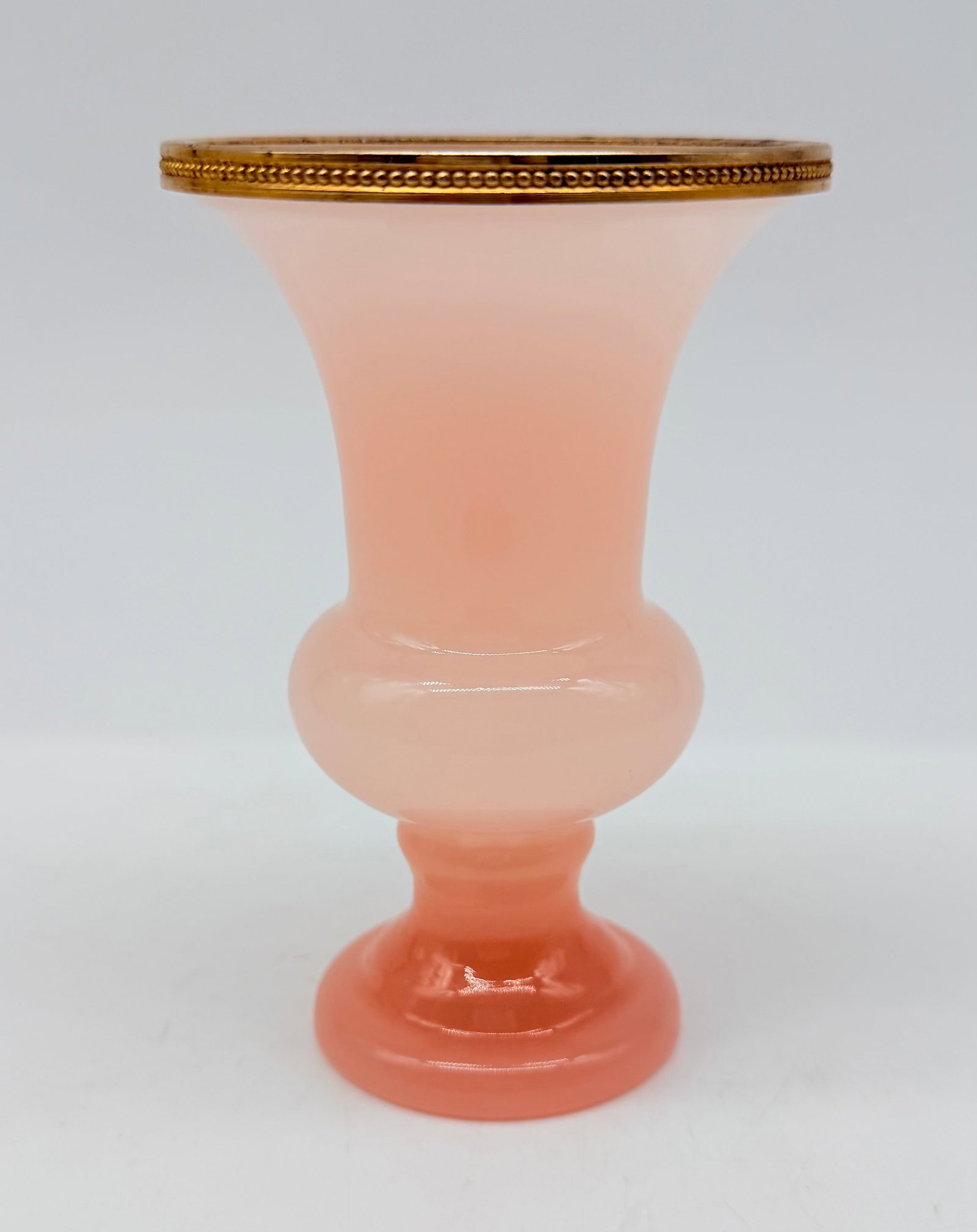 19TH-CENTURY MURANO OPALINE GLASS VASE WITH GILT MOUNT: A pink opaline glass vase featuring a flared rim, a central bulbous node, and a pedestal base. The upper rim is fitted with a beaded gilt-metal mount.Murano, Italy. 19th century.Height: 13.5 cm / Diam